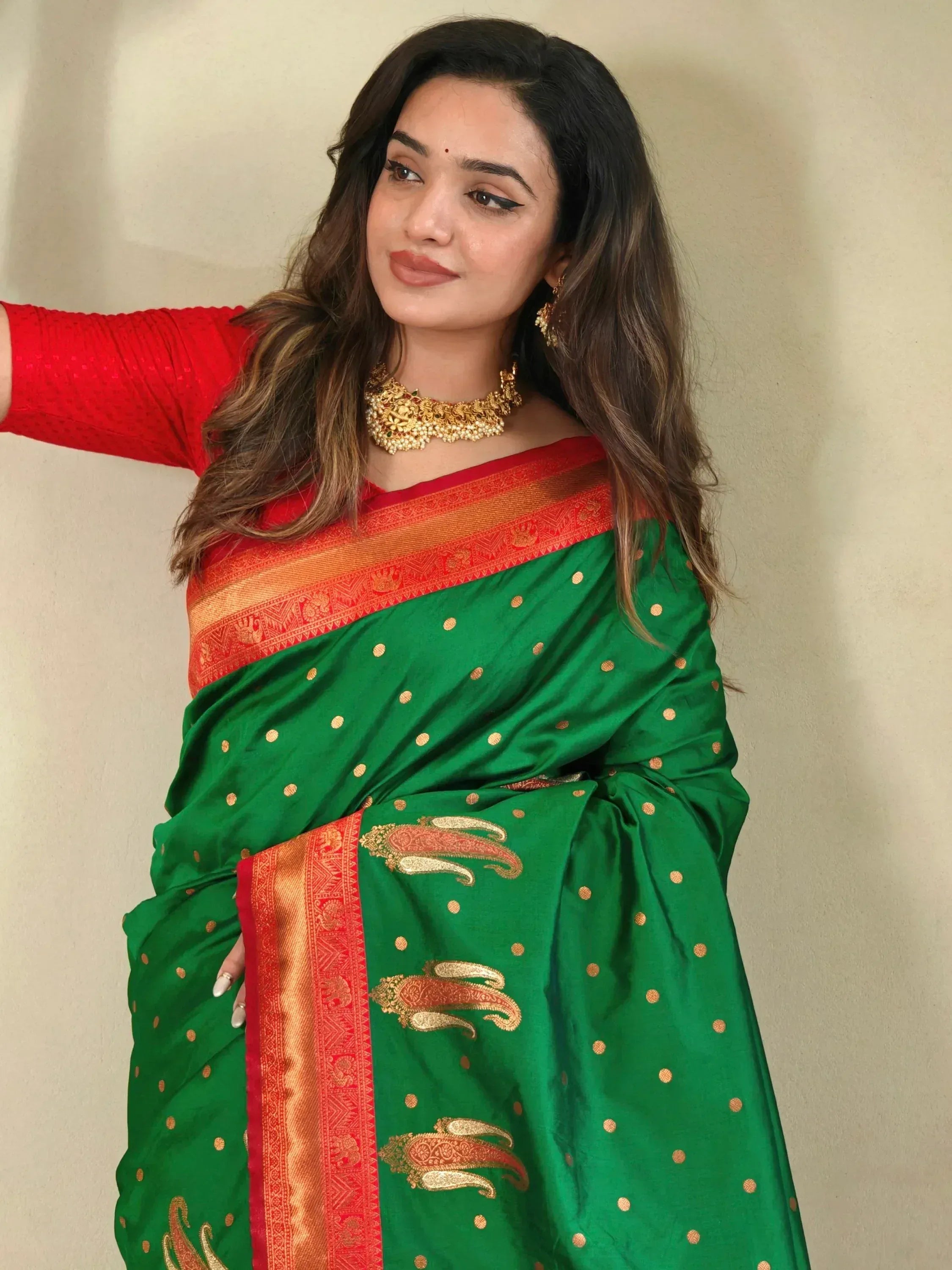 Green saree with gold polka dots and red border, paired with red blouse and gold jewelry