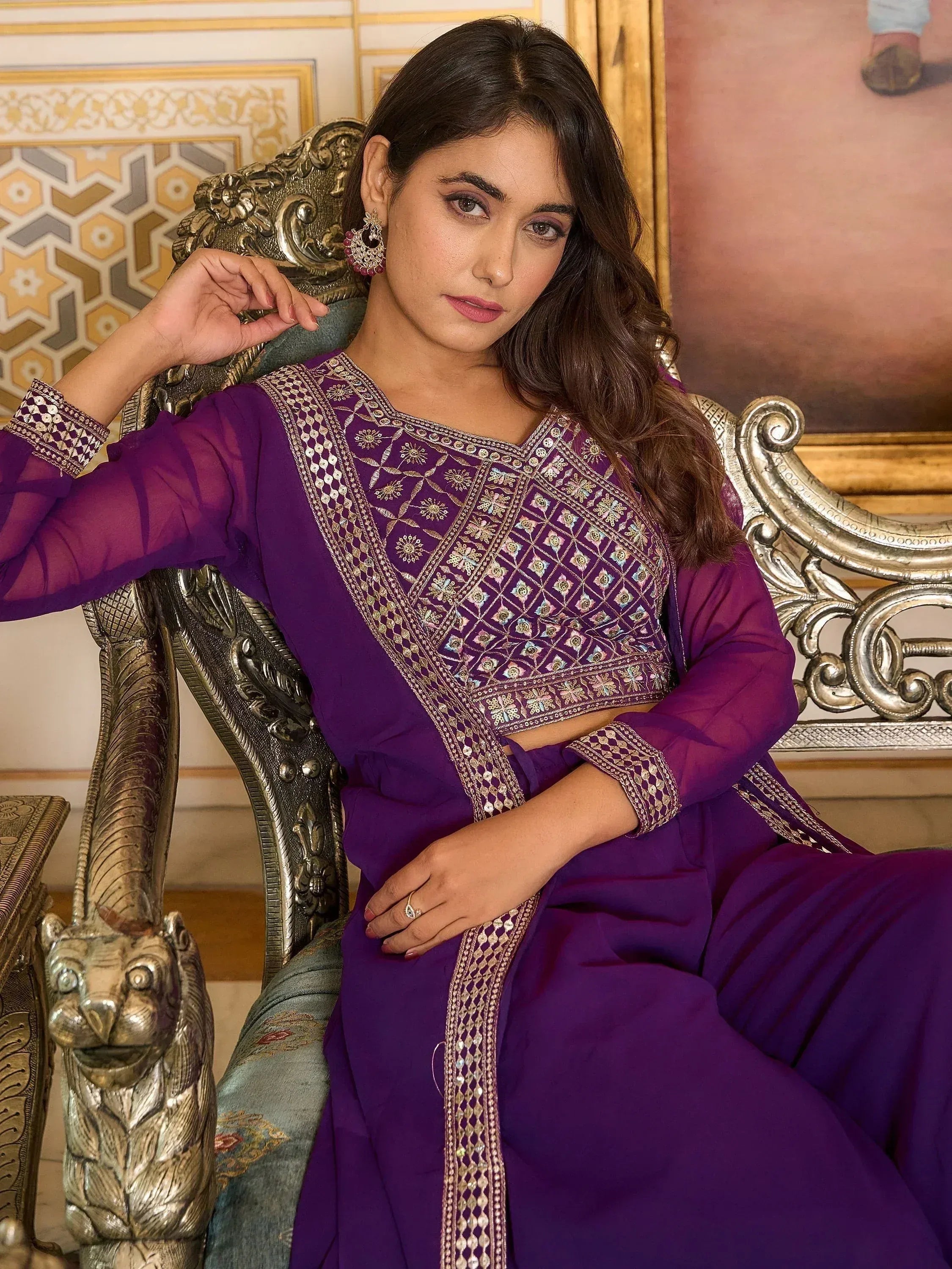 Woman in a purple embroidered Indian ethnic suit sitting on a silver ornate chair