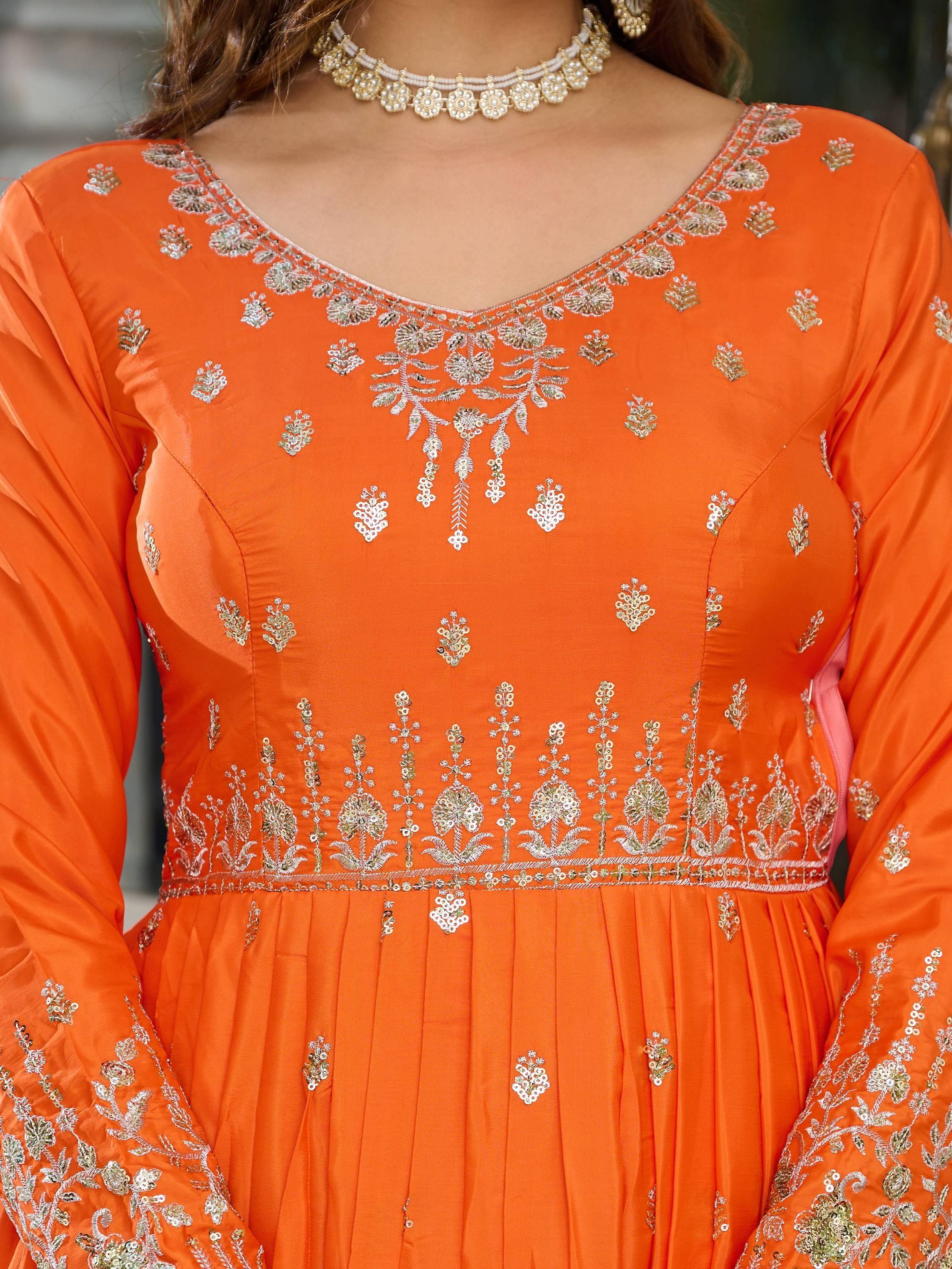Orange ethnic gown with gold floral embroidery and pearl necklace, perfect for Indian occasions