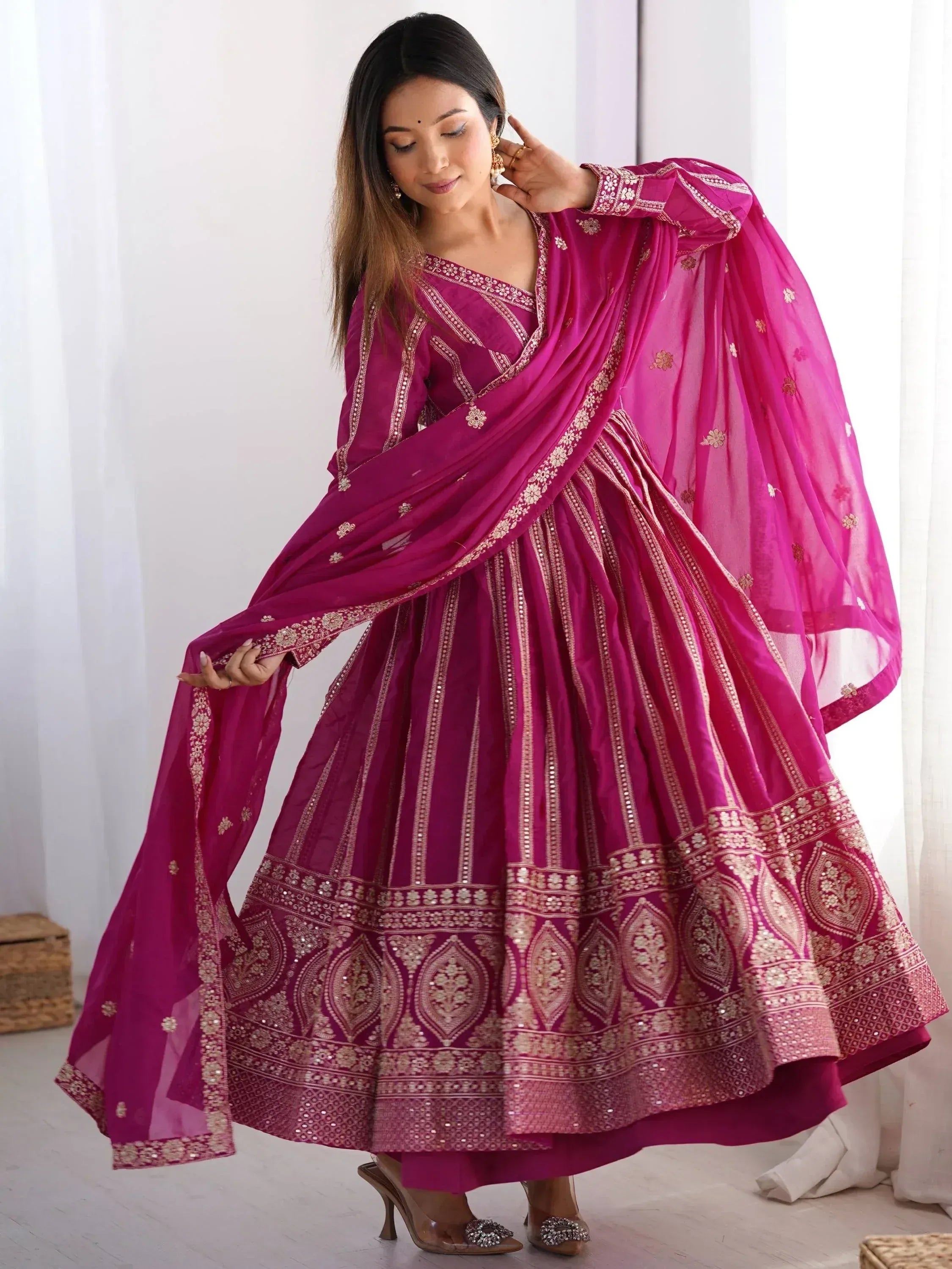 Fuchsia Indian ethnic lehenga choli with gold embroidery and sheer dupatta, perfect for weddings or festivals.