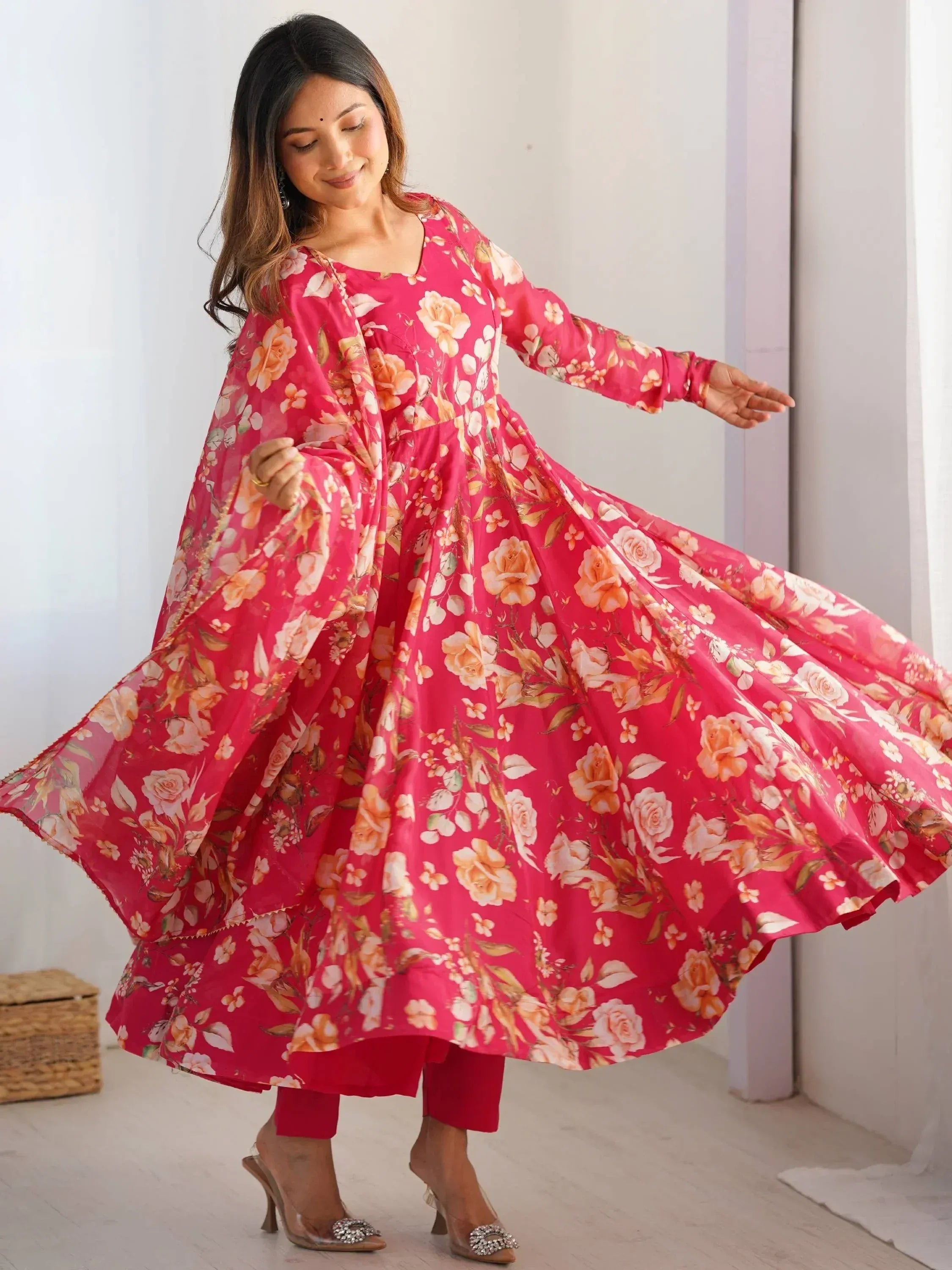 Woman twirling in pink floral ethnic gown with matching dupatta, perfect for Indian occasions