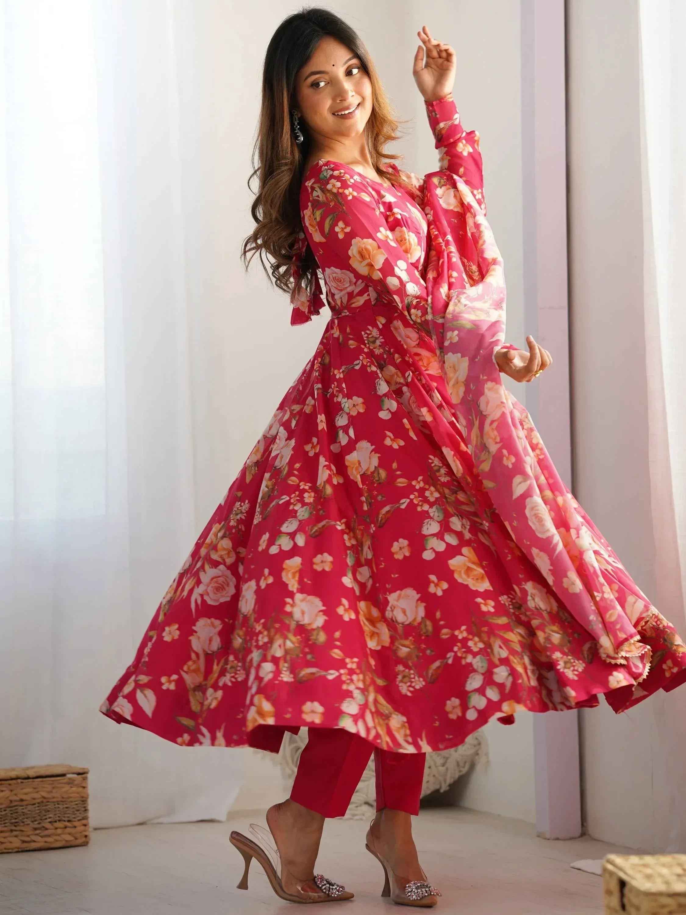 Woman in pink floral ethnic gown with flared sleeves and matching pants, perfect for festive occasions.