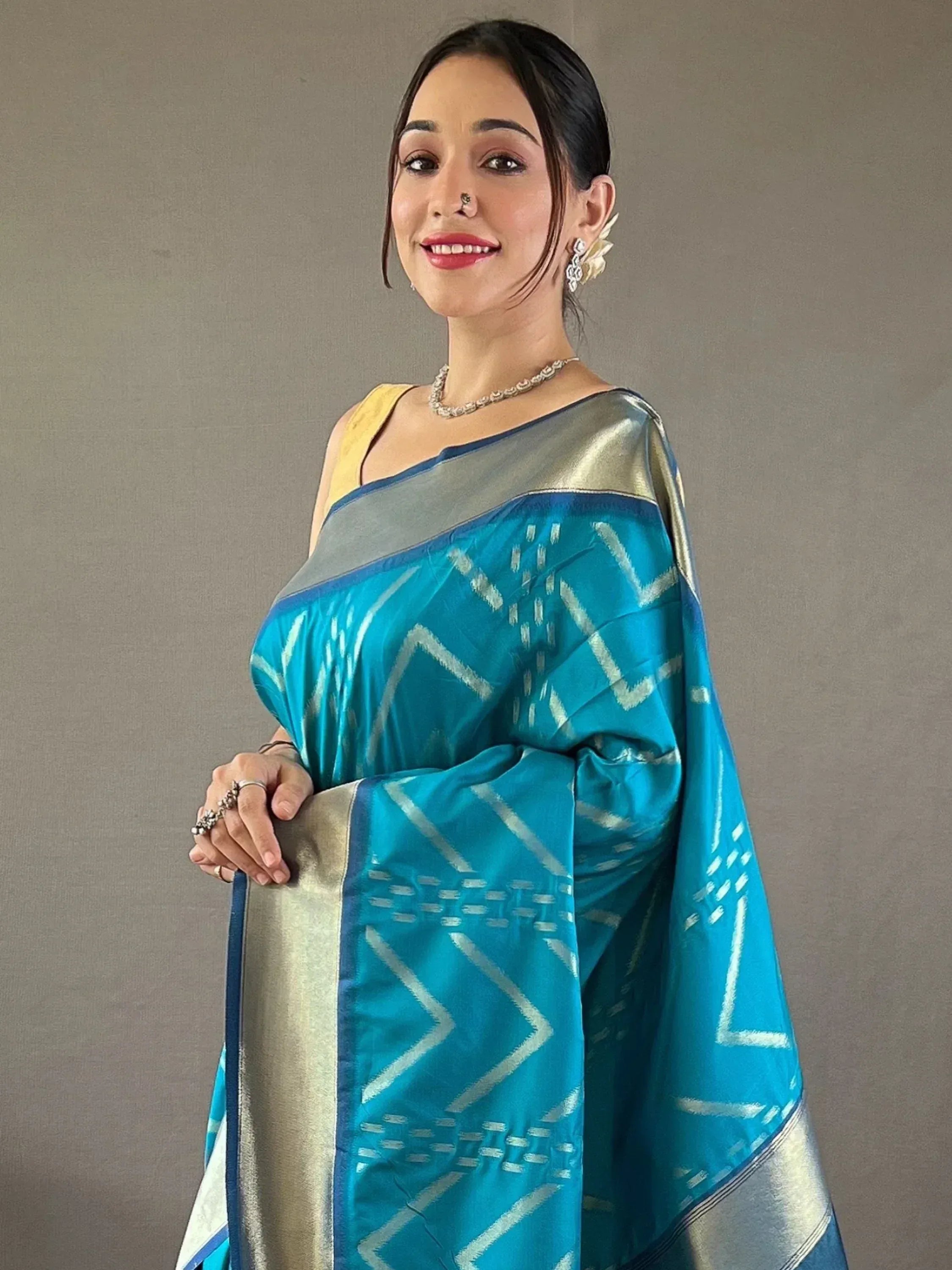 Woman in turquoise Ikat saree with silver geometric patterns, ethnic Indian wear