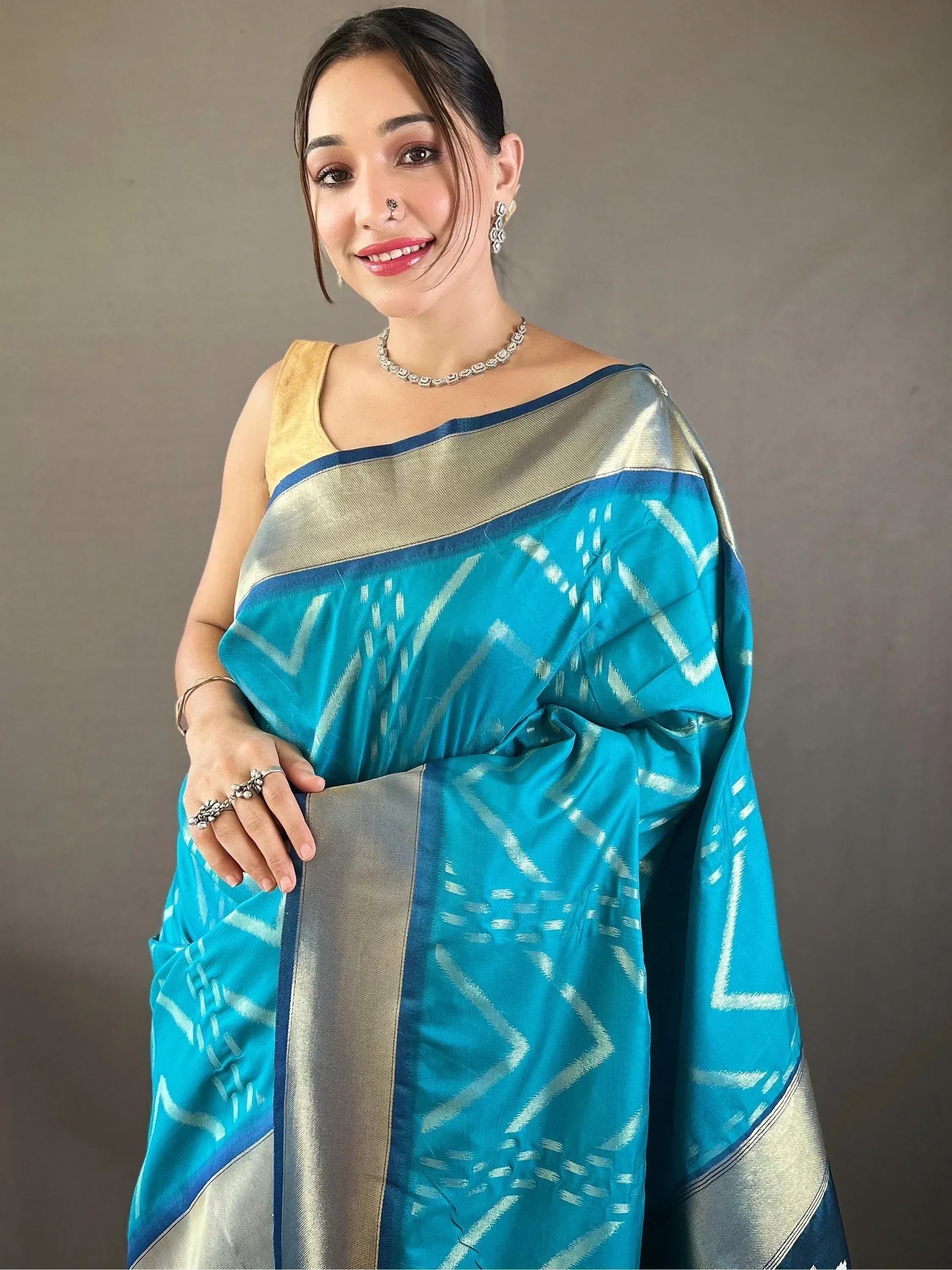 Woman in turquoise ethnic saree with geometric weave and gold border, paired with yellow blouse