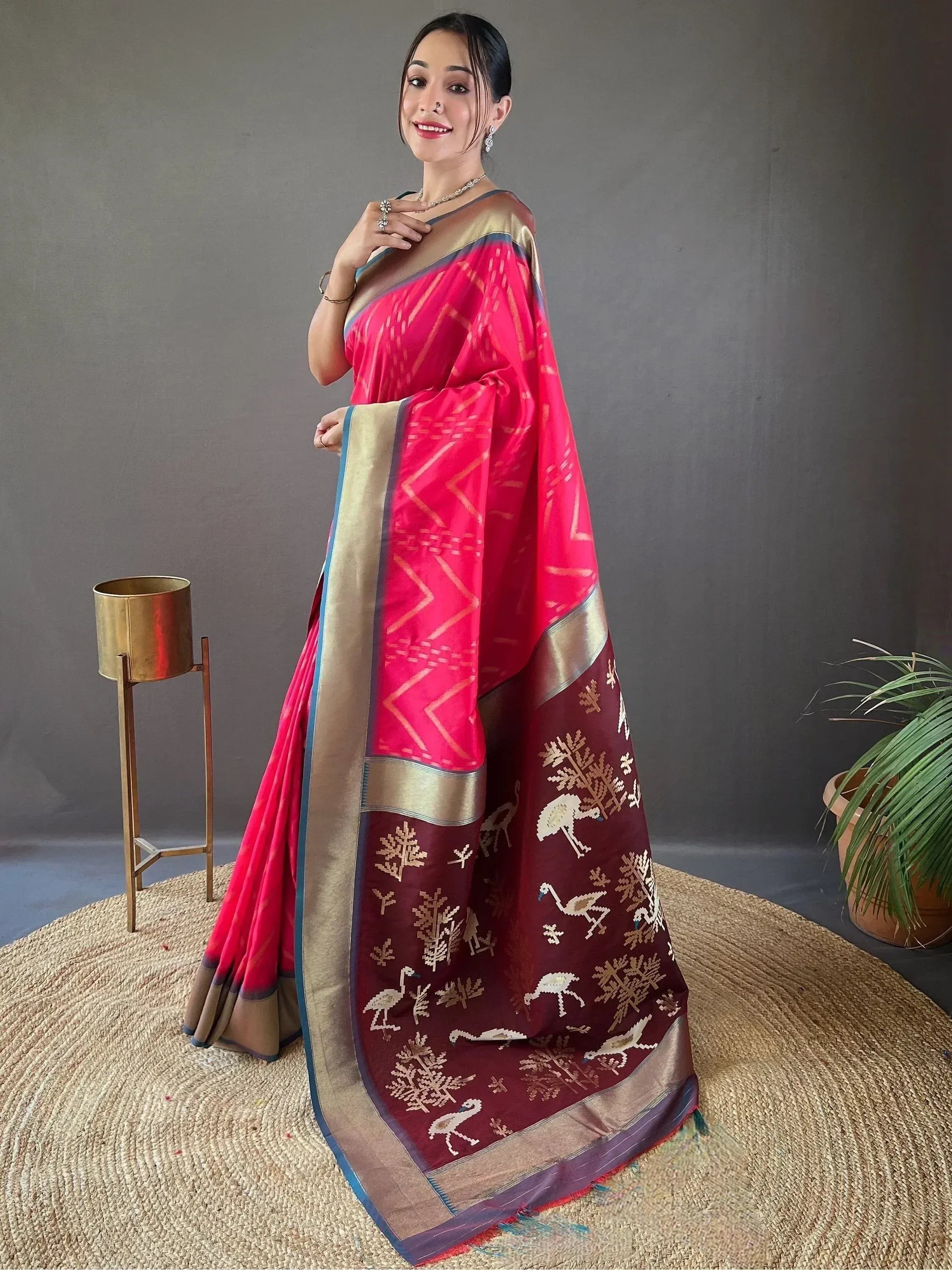 Woman in vibrant pink and maroon ethnic saree with bird and tree motifs, gold border, perfect for Indian occasions
