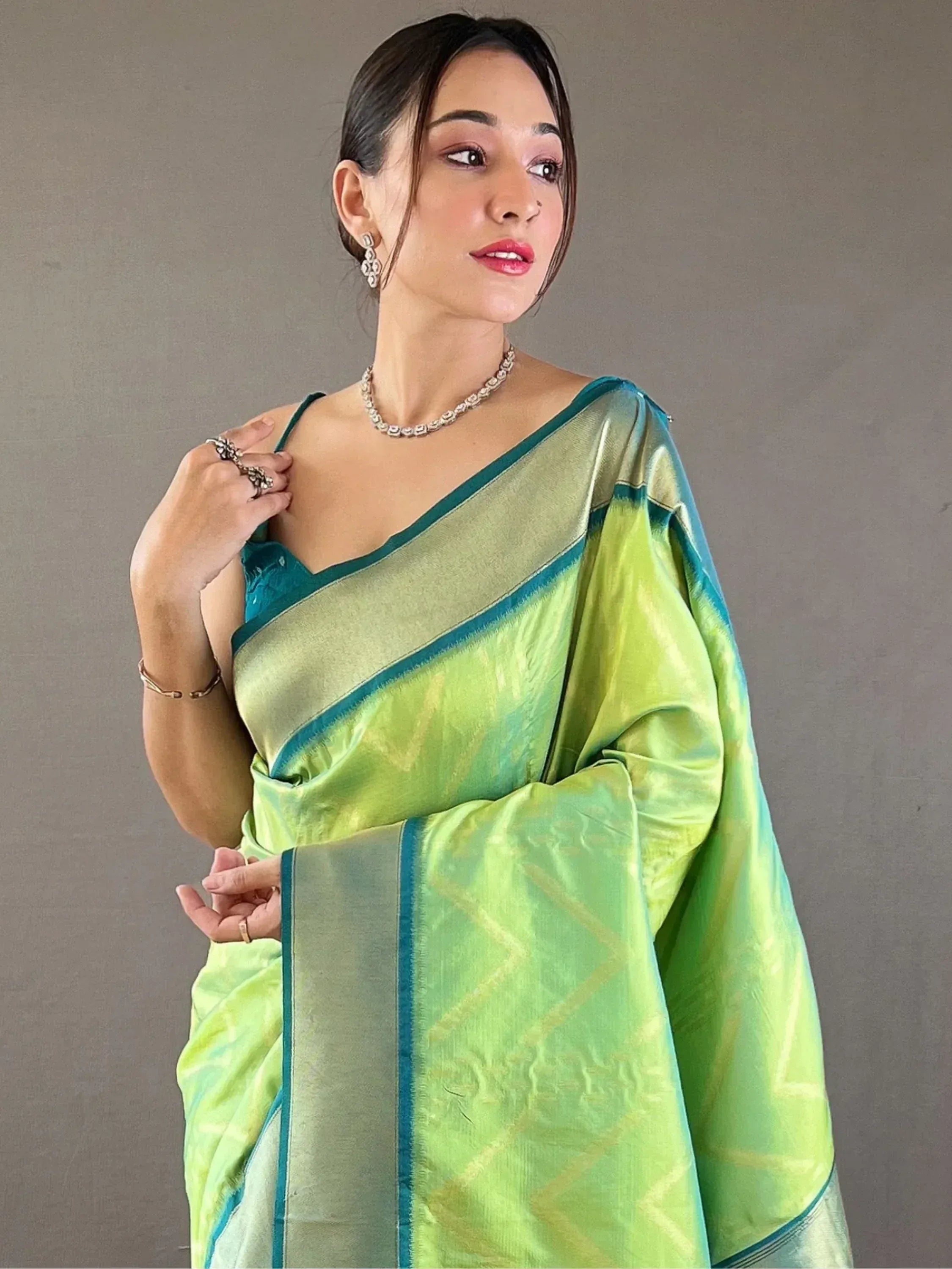 Woman in vibrant green and teal silk saree with geometric pattern, styled with jewelry for ethnic wear