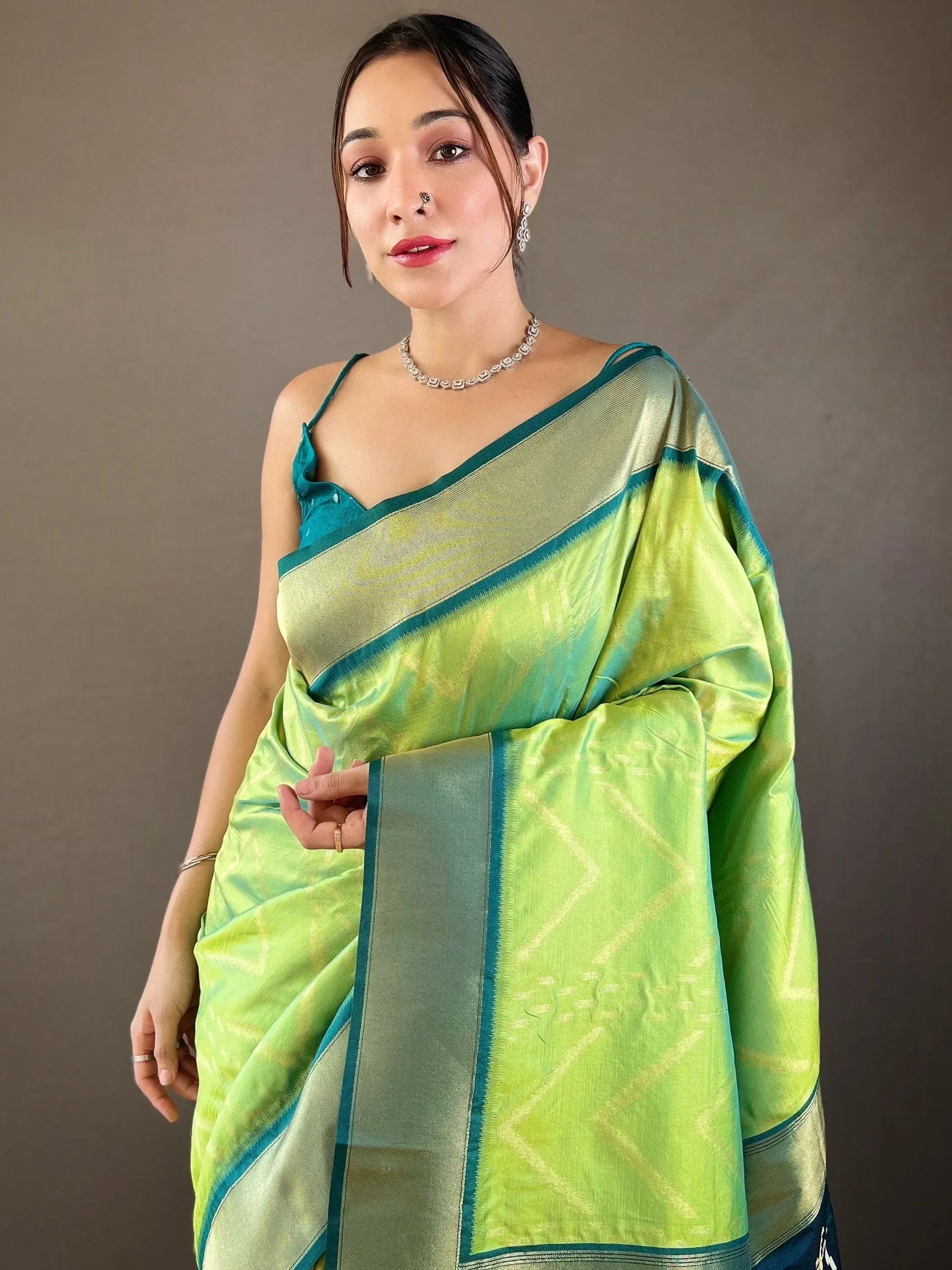 Woman in vibrant green and teal silk saree with geometric patterns, styled for ethnic occasions