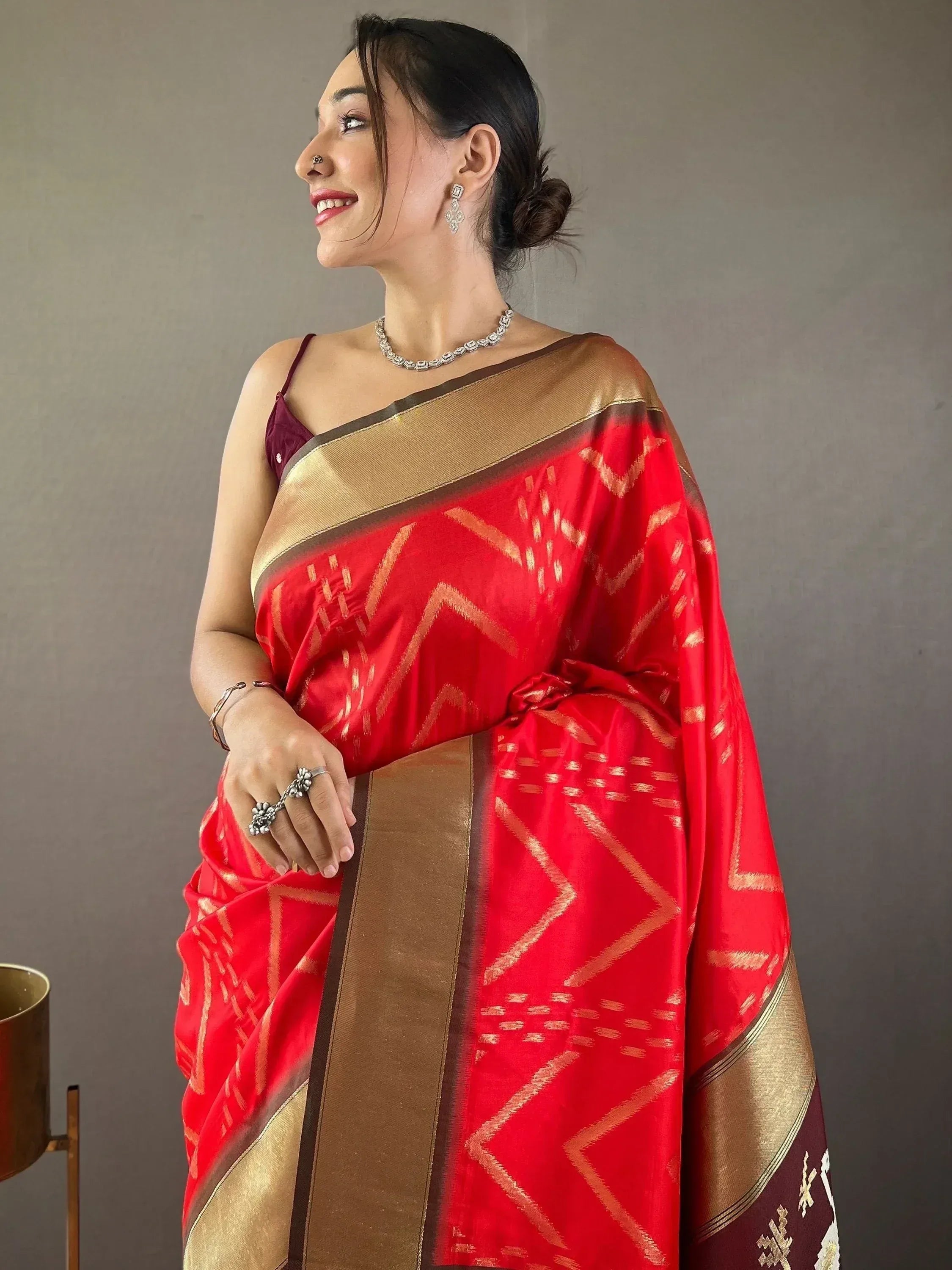 Red and gold ethnic saree with geometric patterns, styled with jewelry for Indian occasions