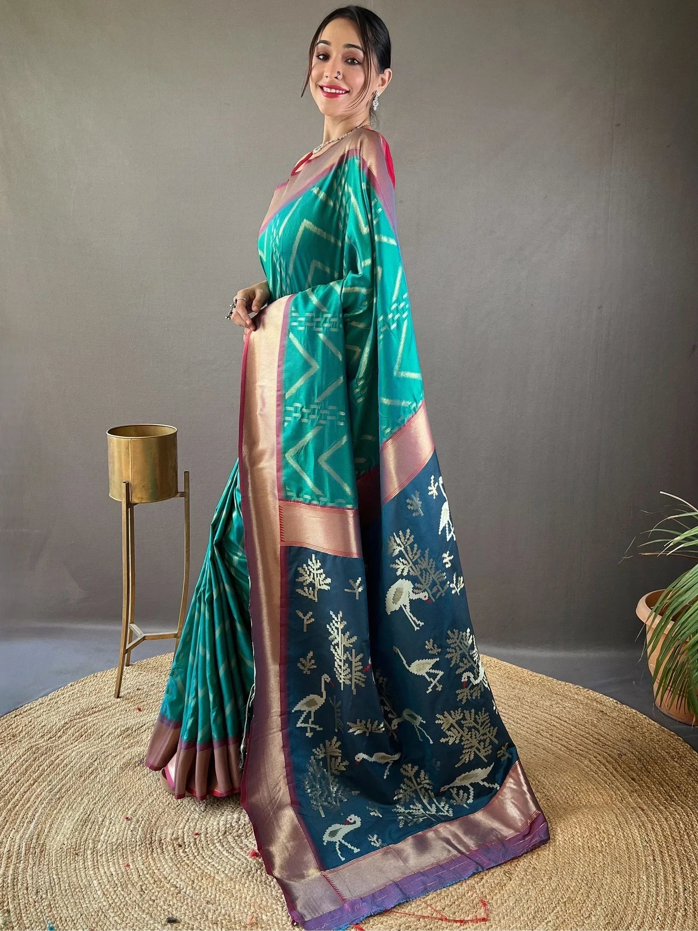 Woman in teal and navy designer saree with geometric and bird motifs, ethnic wear for festive occasions