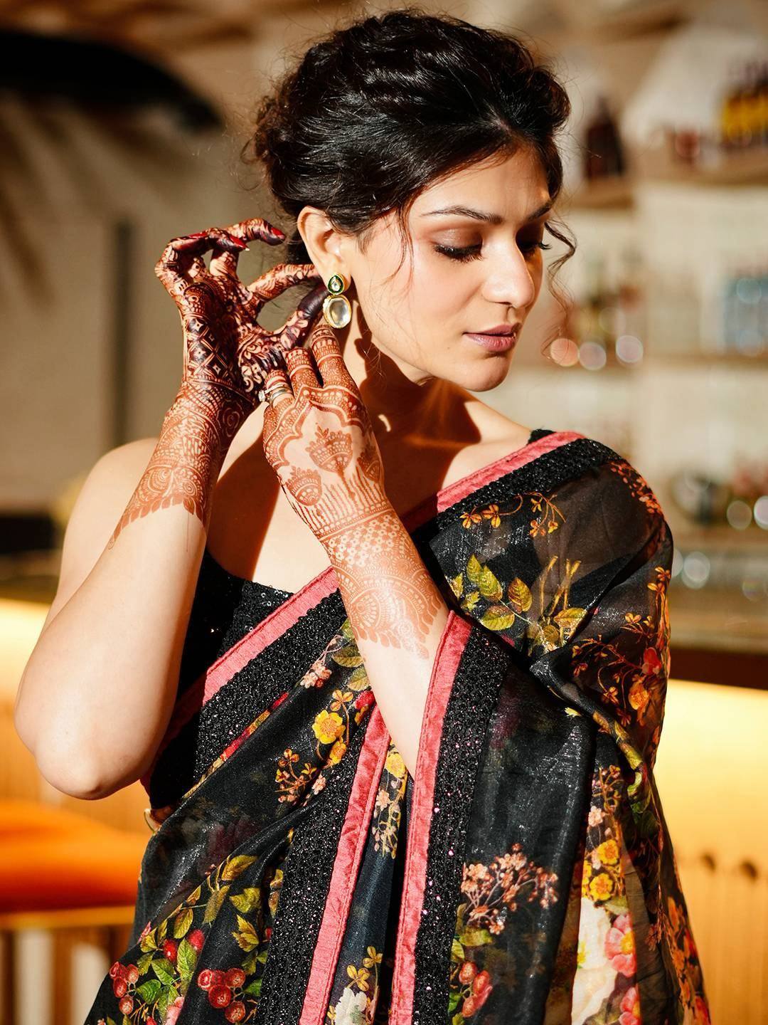 Woman in black floral saree with henna hands, elegant ethnic wear for special occasions