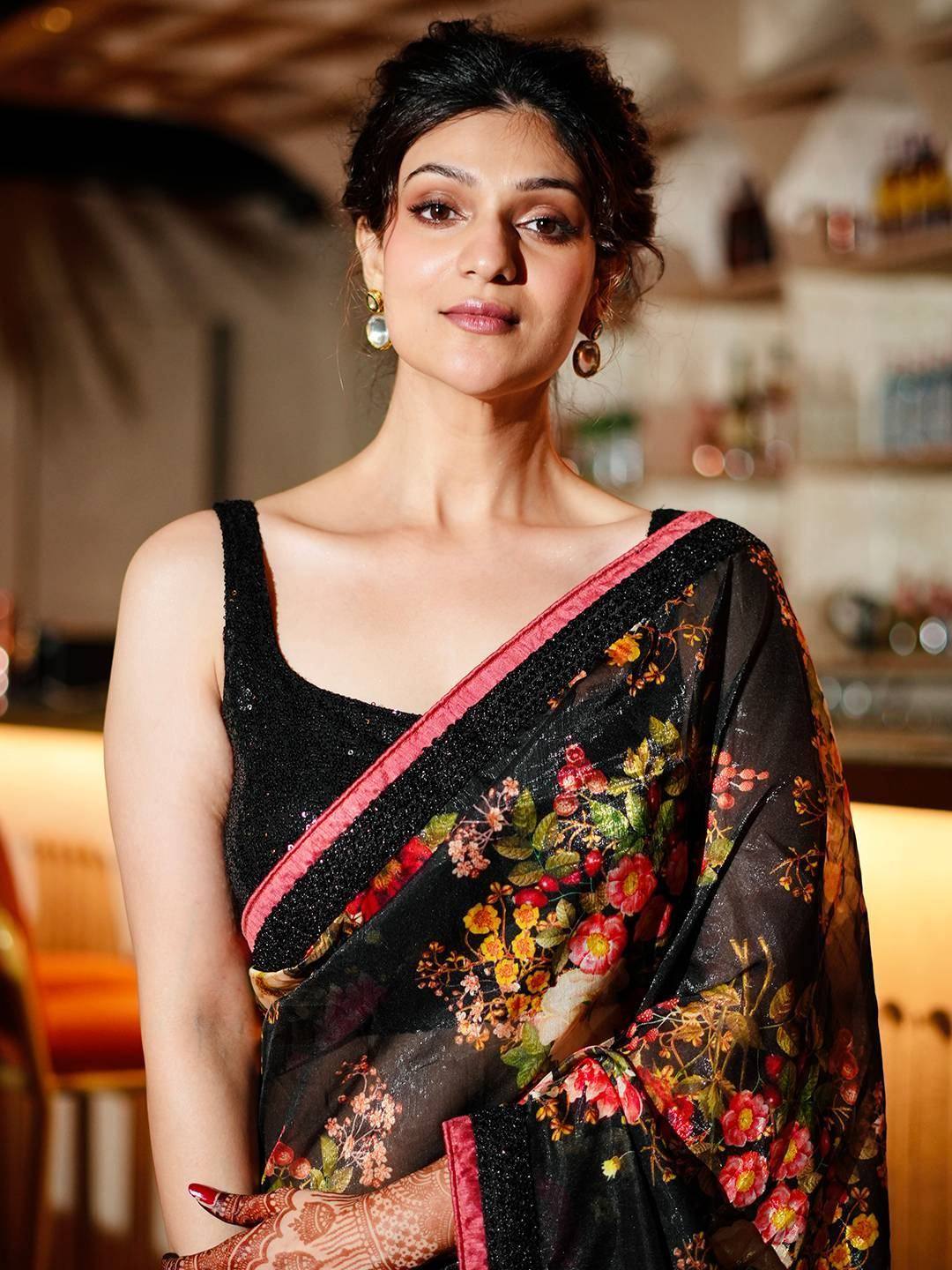 Black floral saree with pink border, paired with sequined blouse, perfect for ethnic occasions