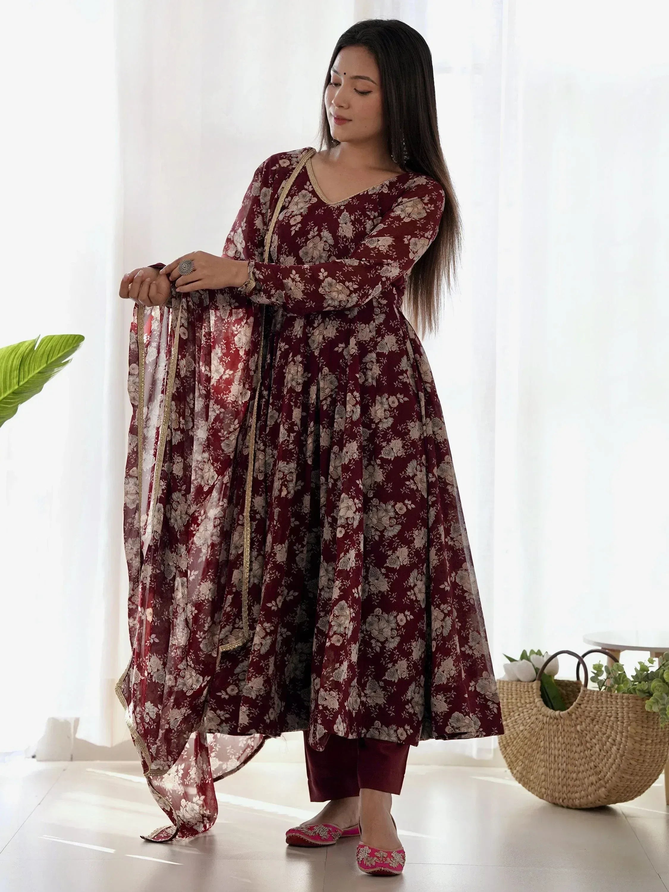 Maroon floral printed Anarkali suit with gold trim, paired with matching dupatta and pink juttis for ethnic wear.