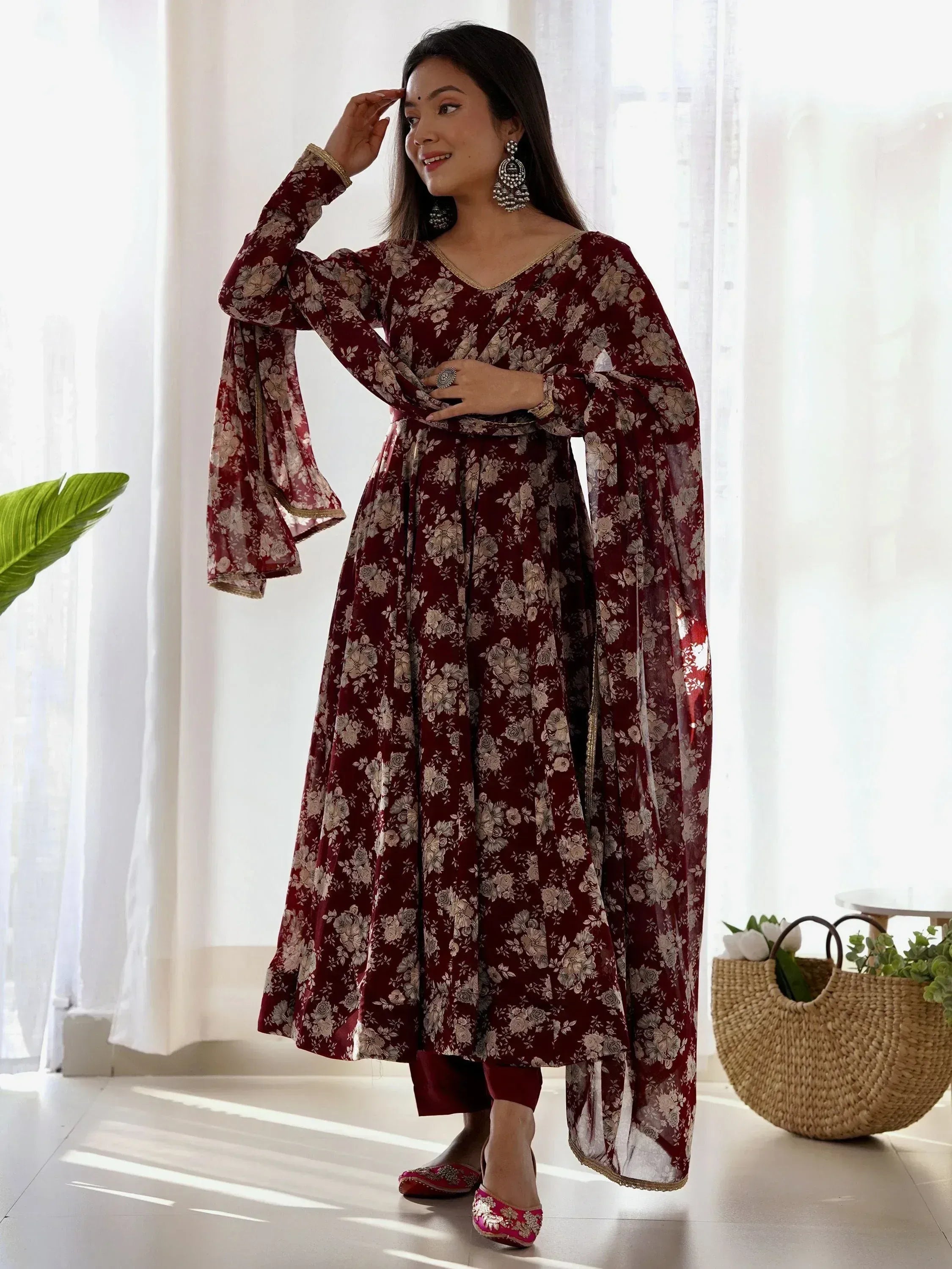 Maroon floral print ethnic gown with bell sleeves and gold trim, styled with juttis and statement earrings