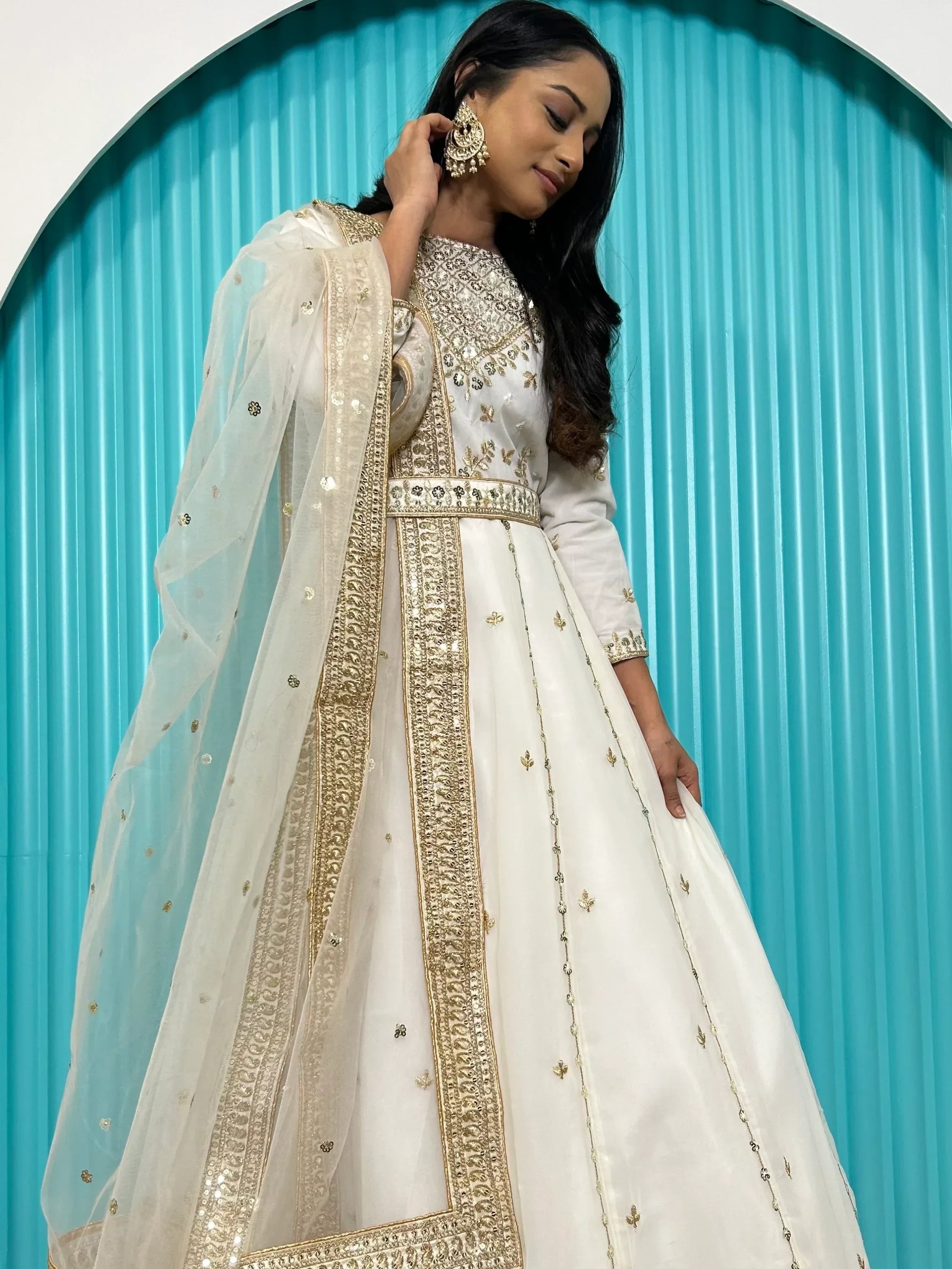 Woman in a white and gold embroidered lehenga choli with sheer dupatta, Indian ethnic wear