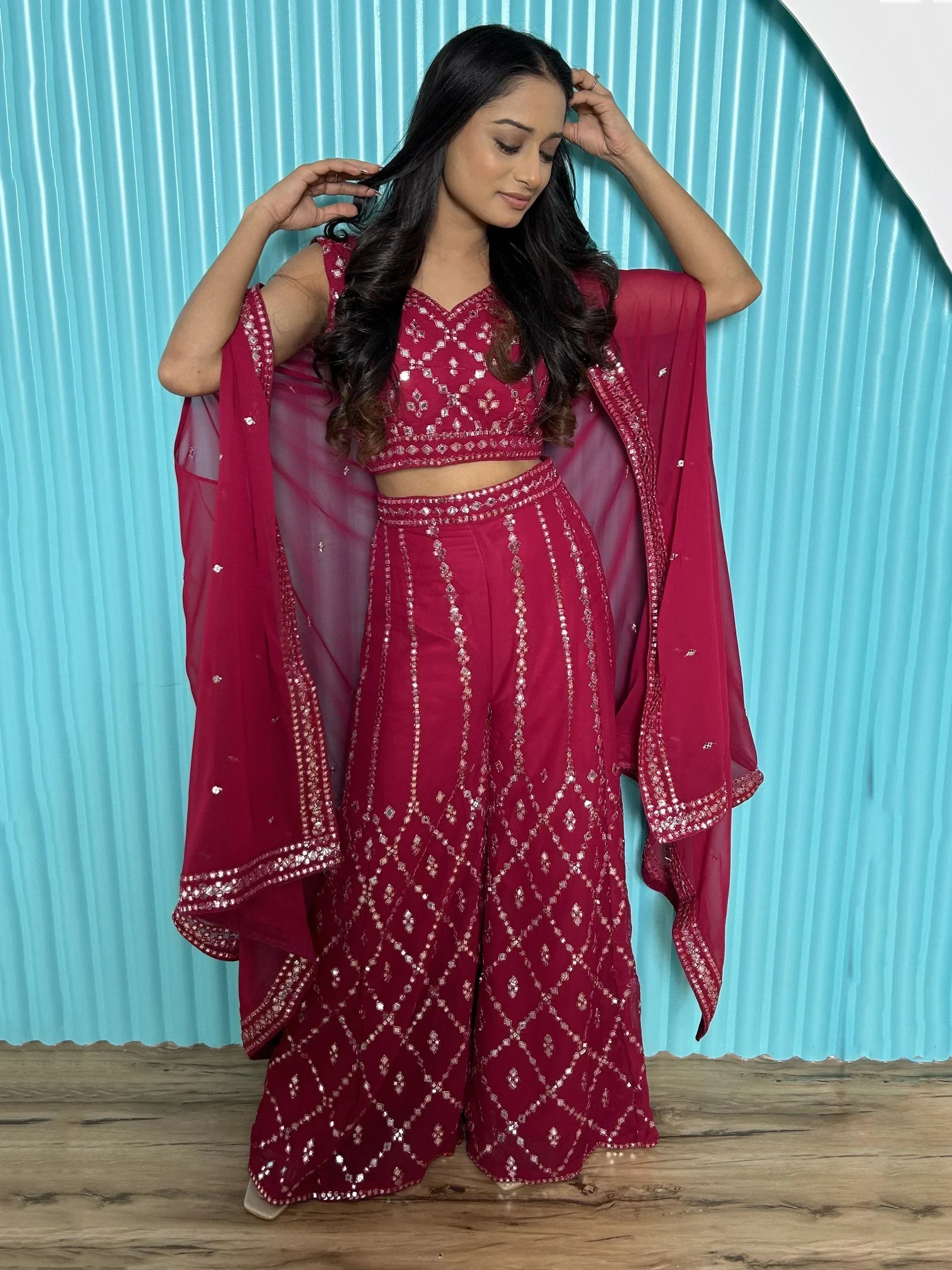 Woman wearing a maroon embroidered lehenga choli with dupatta, standing indoors