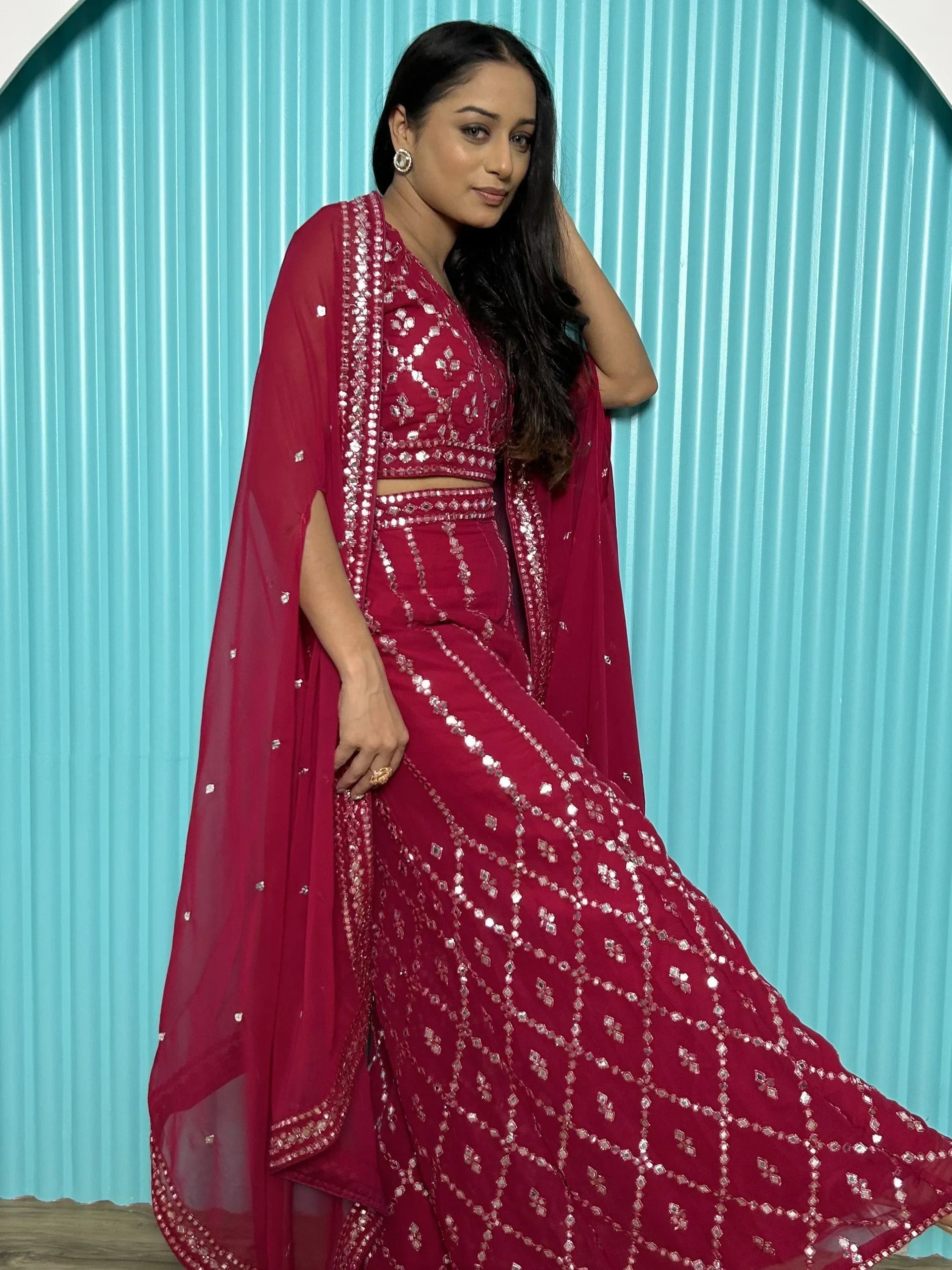 Woman in a magenta mirror work lehenga choli with dupatta, posing indoors