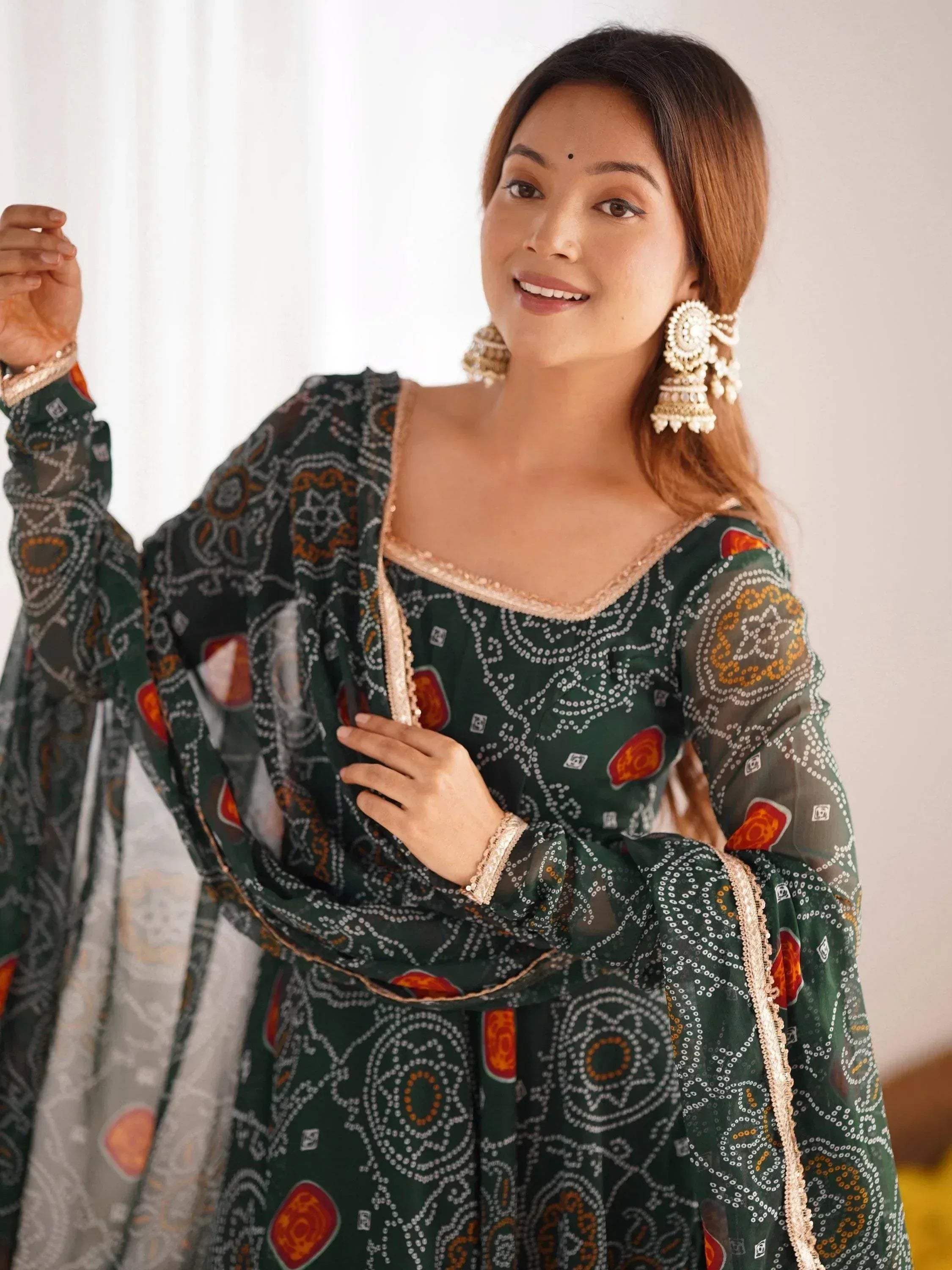 Woman in green printed ethnic gown with gold trim and jhumka earrings, Indian festive wear