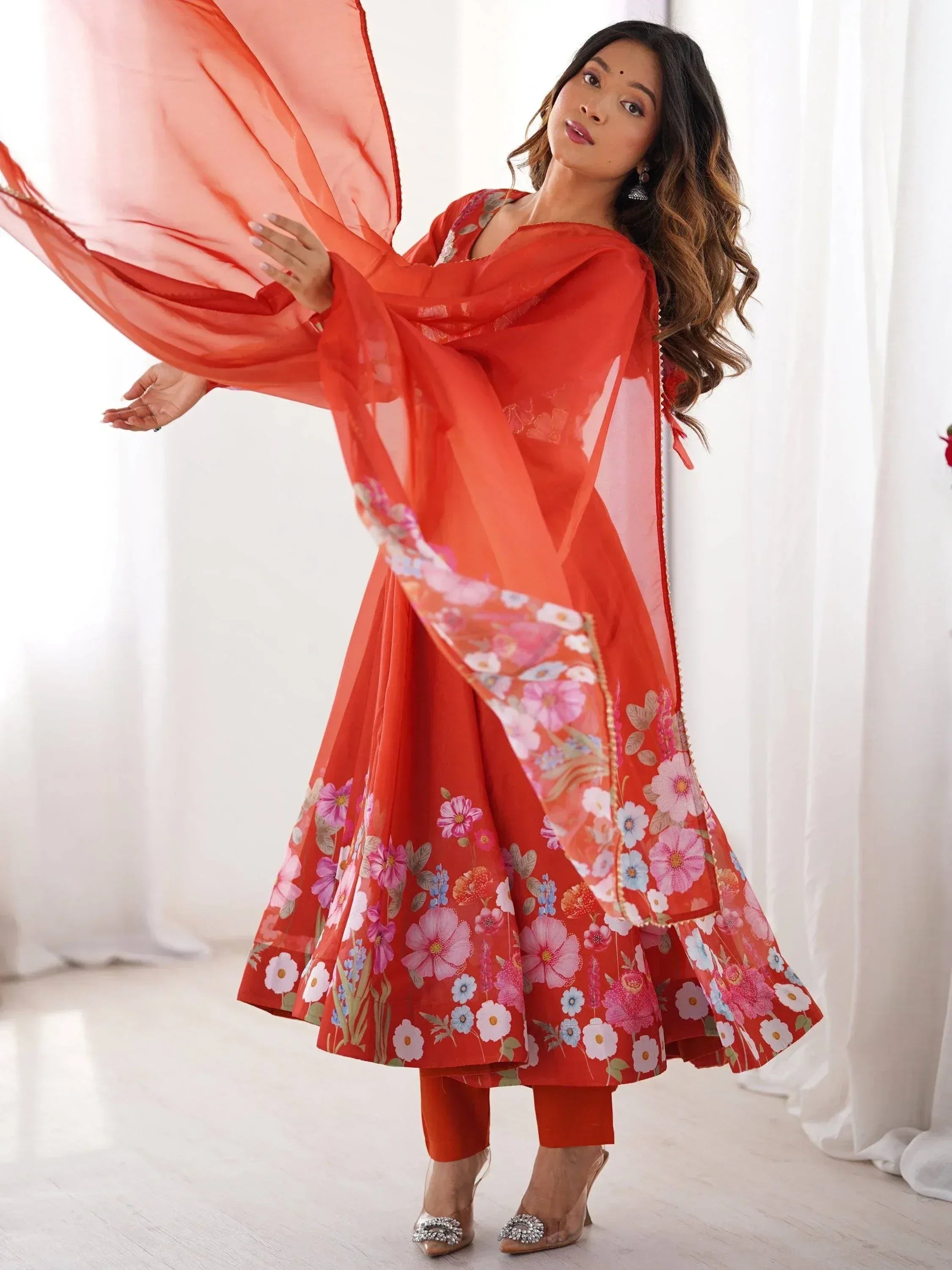 Woman in vibrant orange floral print salwar kameez with matching dupatta, elegant ethnic wear for festive occasions