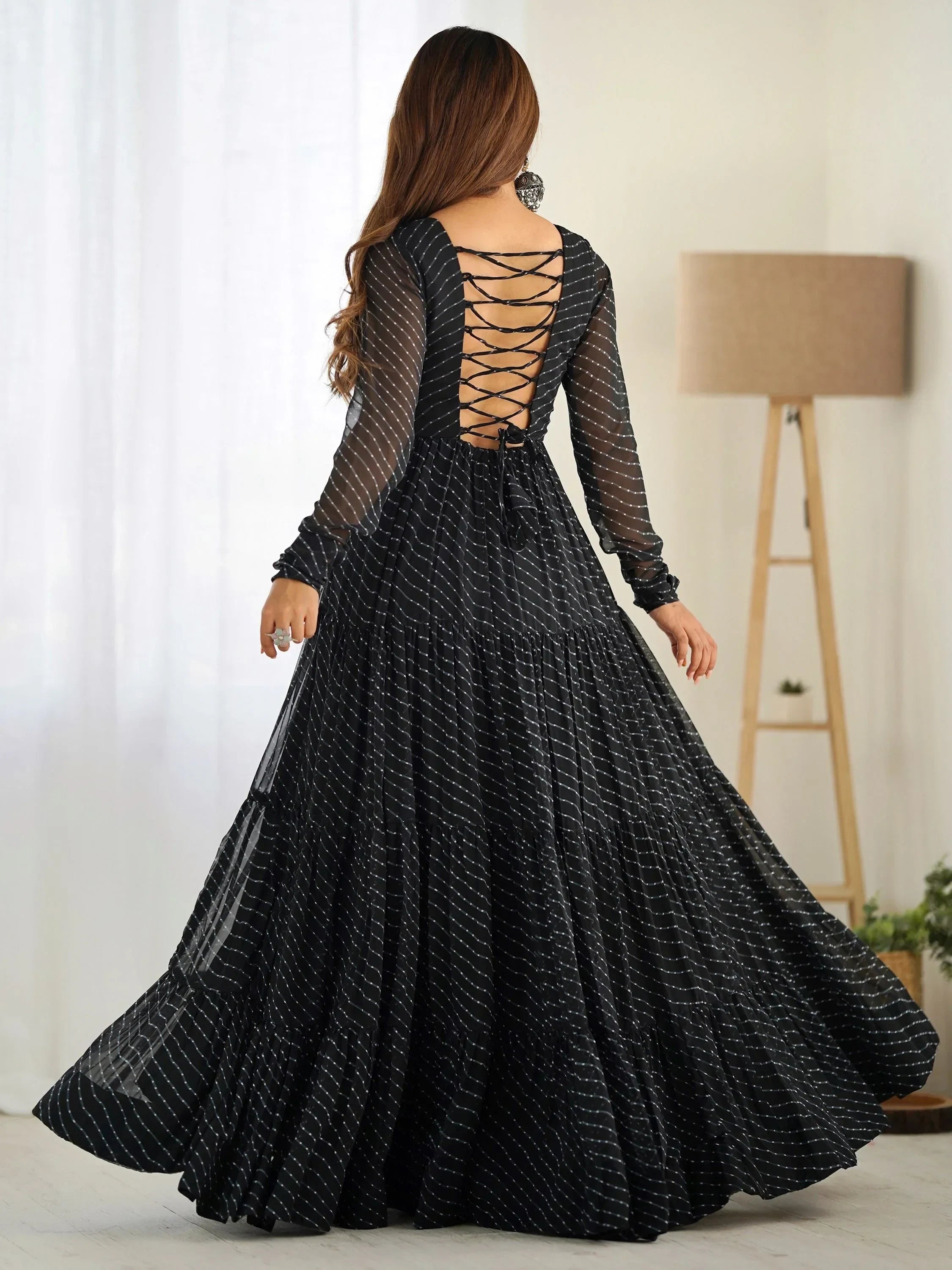 Woman in black ethnic gown with long sleeves and criss-cross back, indoors