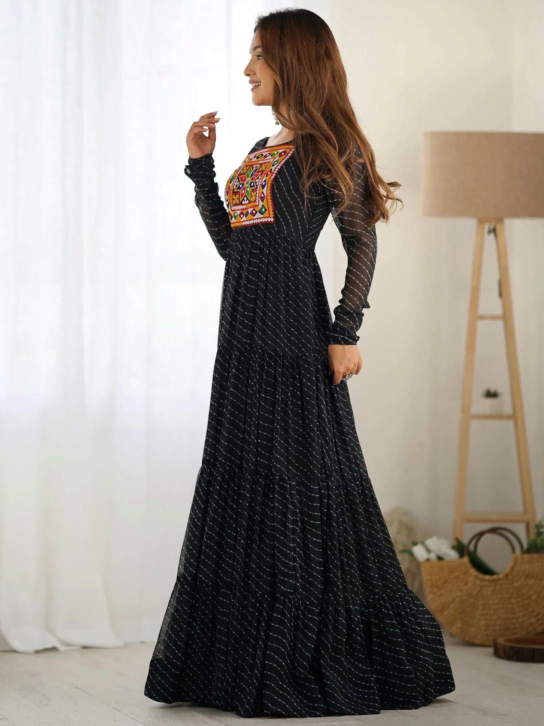 Woman wearing black embroidered ethnic gown with long sleeves in modern living room