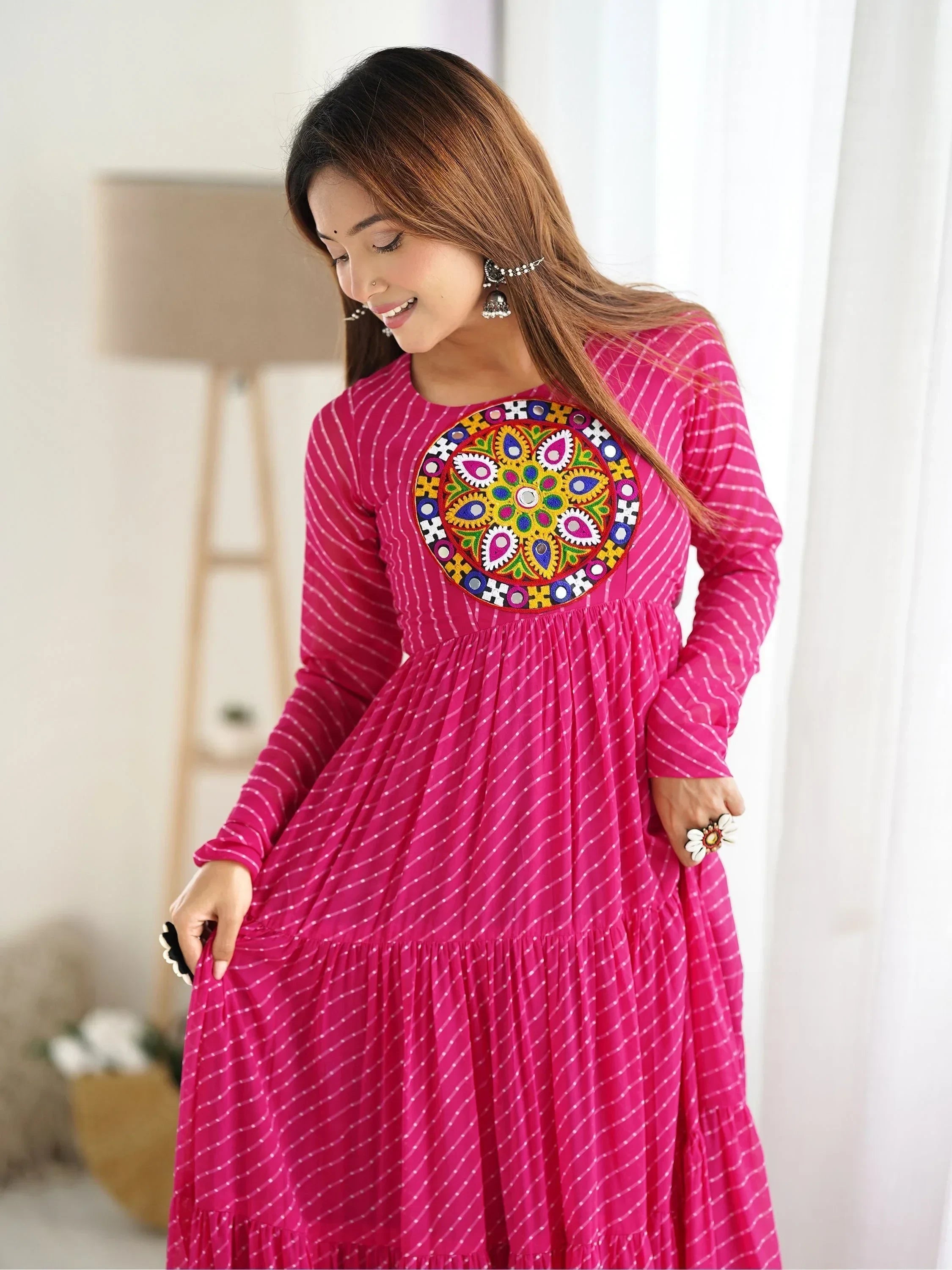 Woman in pink long ethnic gown with mirror work yoke and silver jhumka earrings