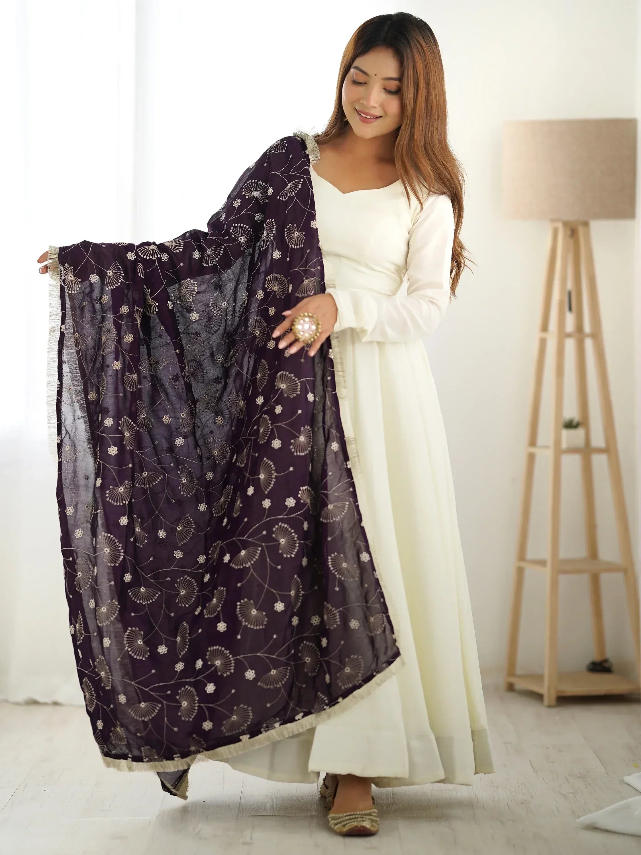 Woman in white ethnic gown with purple floral dupatta, showcasing Indian designer wear