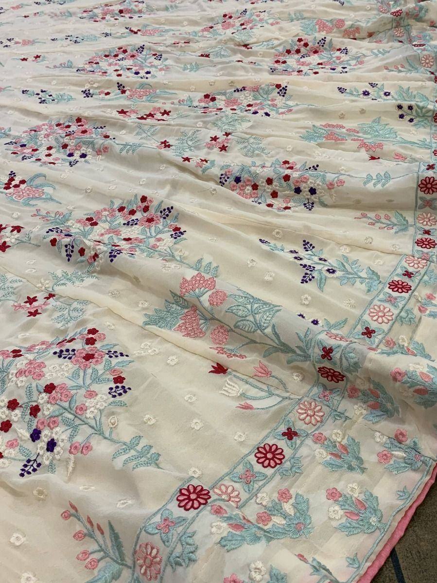 Floral embroidered ethnic saree with pink, red, and blue motifs on cream fabric