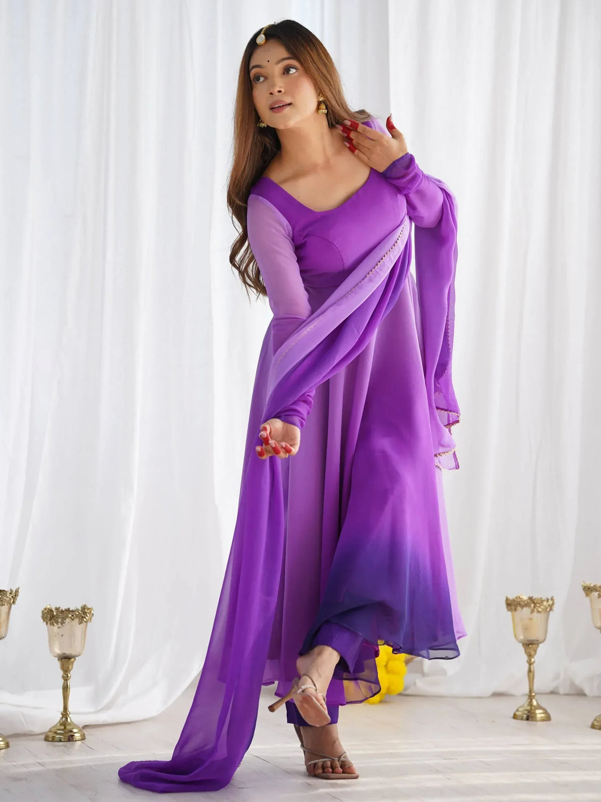 Purple ethnic gown with sheer overlay and gold trim, styled with traditional jewelry for festive occasions