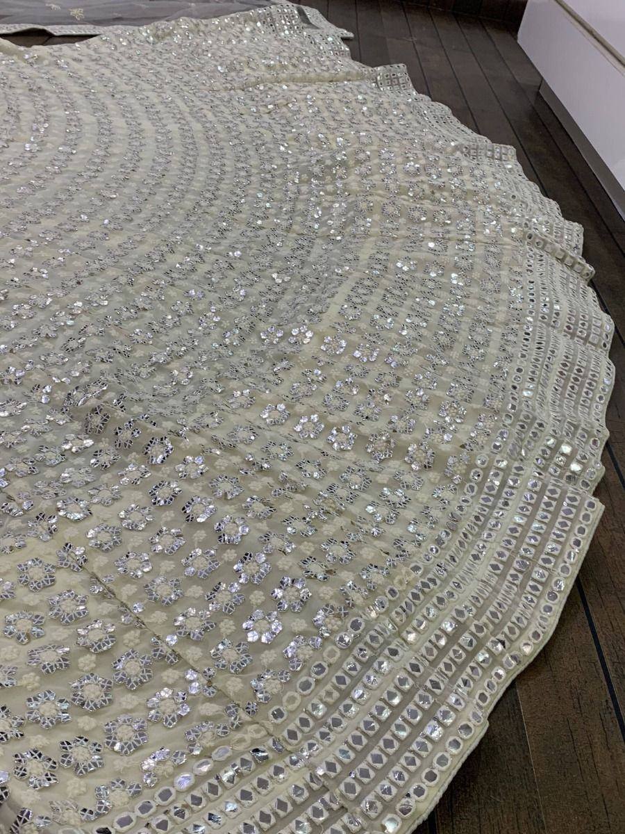 Cream ethnic lehenga with intricate mirror and sequin embroidery, perfect for Indian weddings and festive occasions.