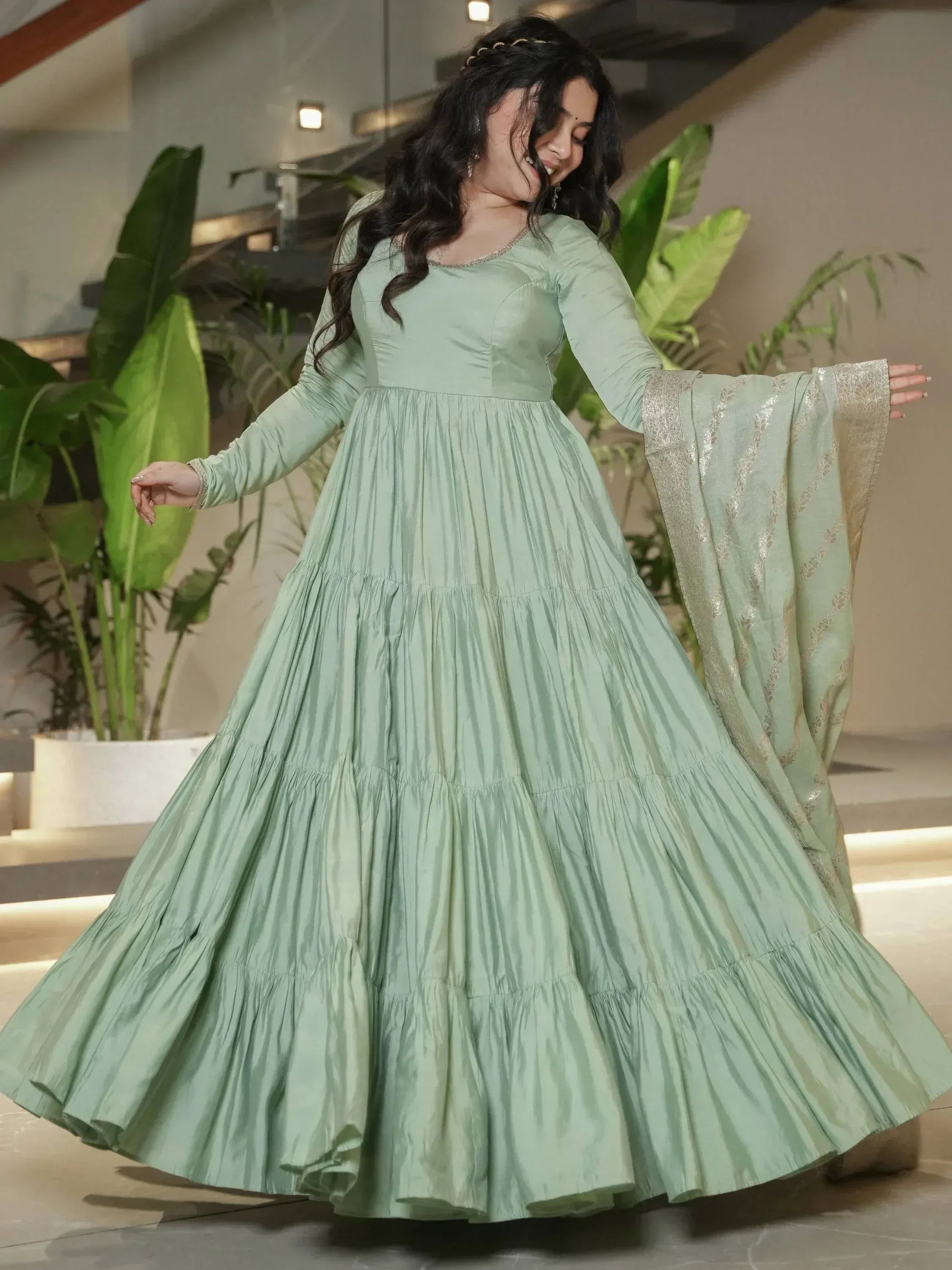Mint green tiered ethnic gown with gold trim, perfect for Indian festive occasions and parties.