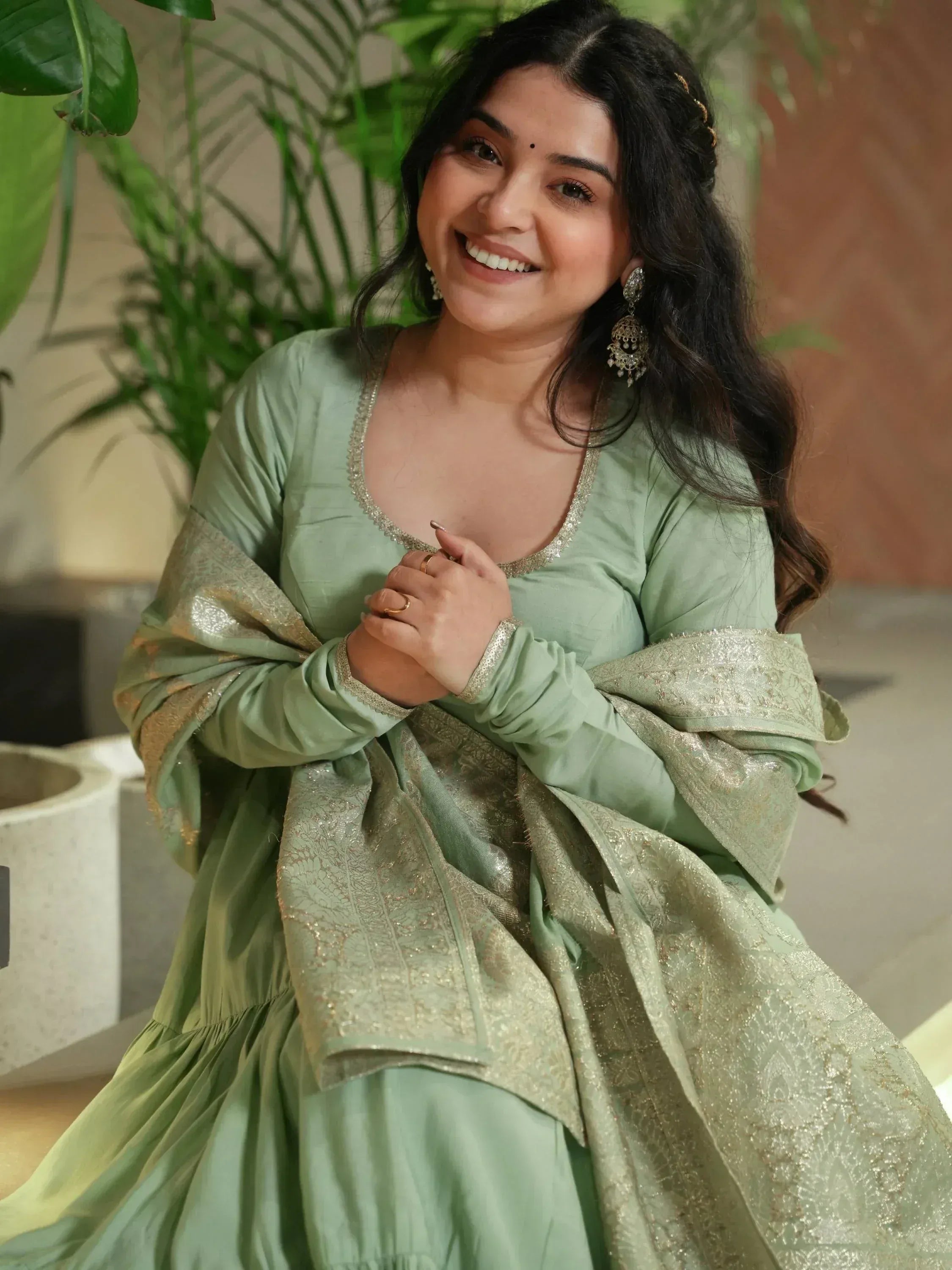 Woman in mint green ethnic gown with gold embroidery, perfect for Indian occasions and festive wear.