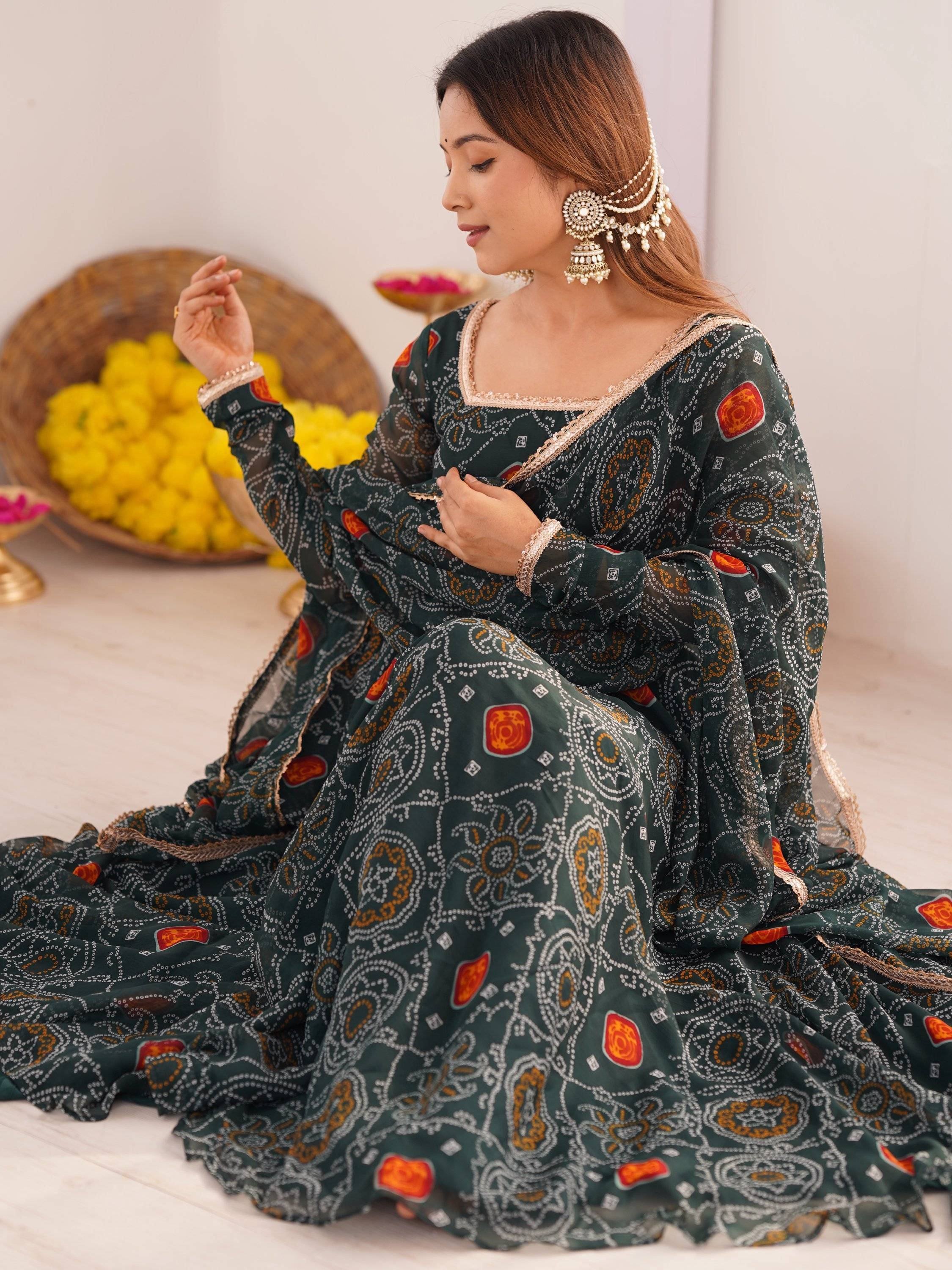 Woman in green printed ethnic gown with gold trim, traditional jewelry, and yellow flowers background