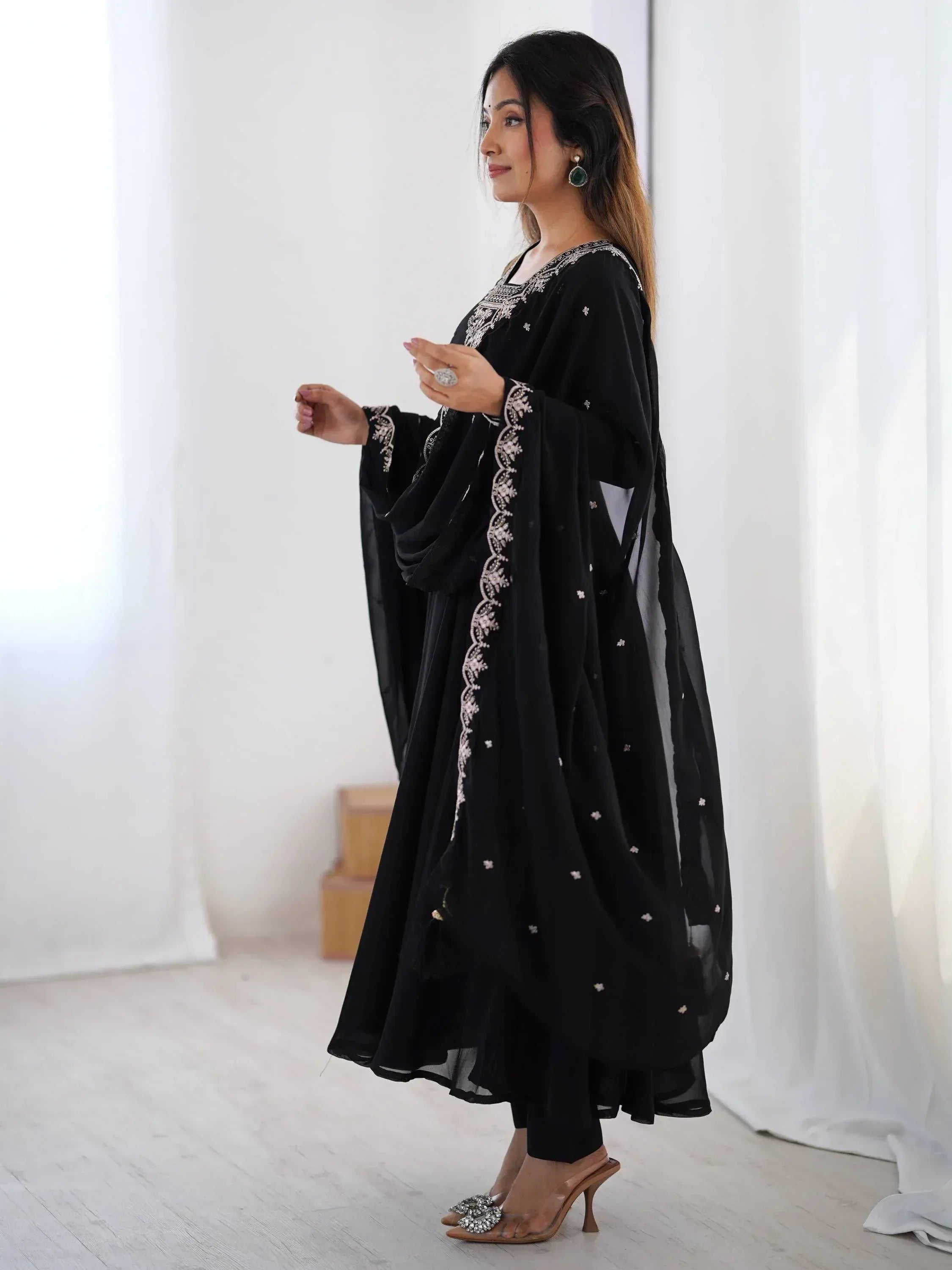 Black embroidered ethnic gown with flared sleeves and floral detailing, styled with heels for festive occasions