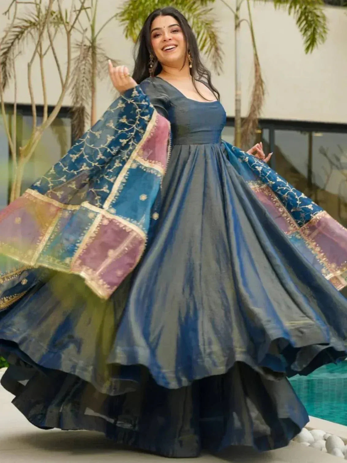 Woman twirling in elegant blue ethnic gown with embroidered dupatta, perfect for Indian festive occasions