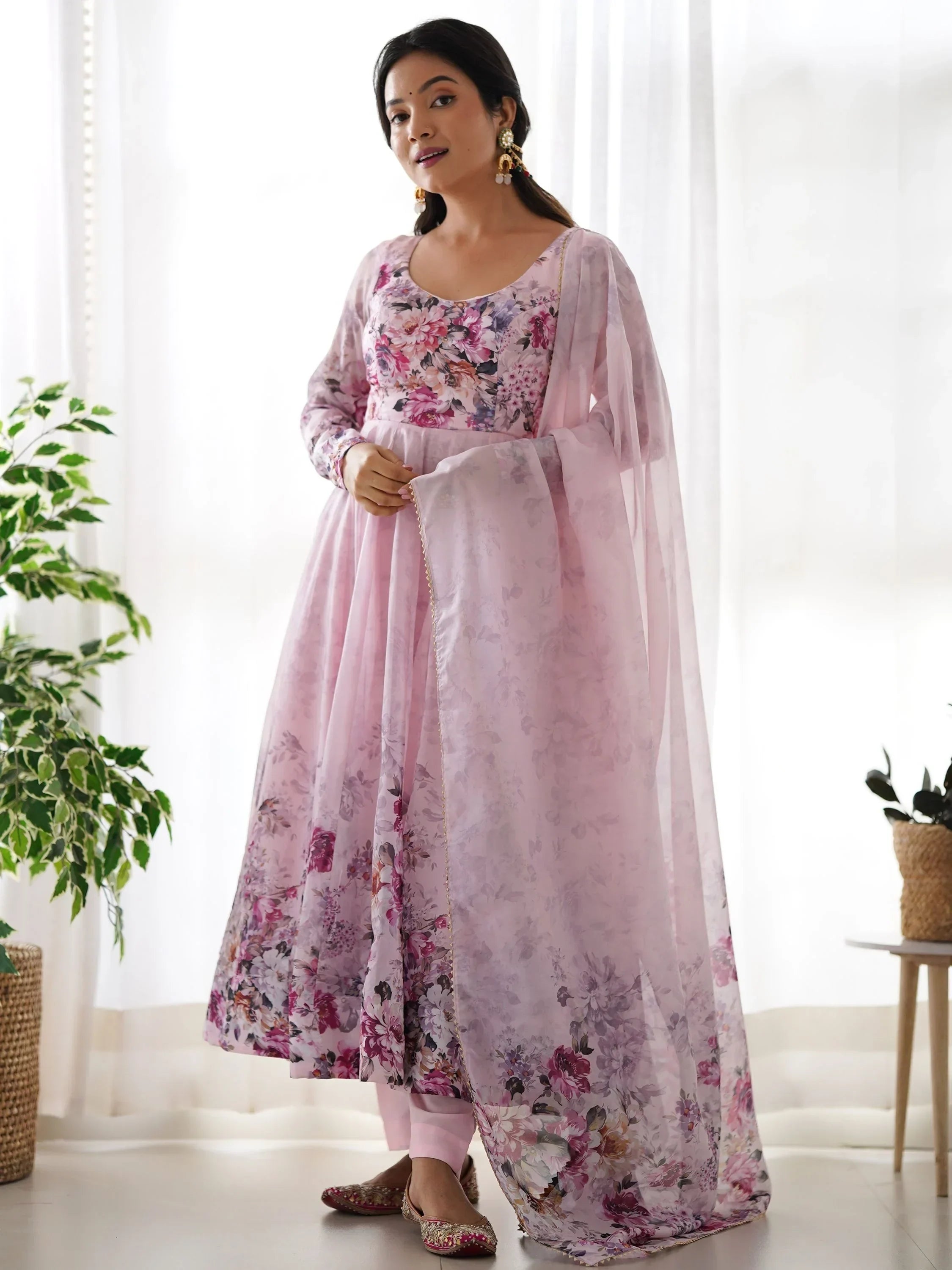 Woman wearing a light pink floral printed ethnic gown with matching dupatta in a bright room