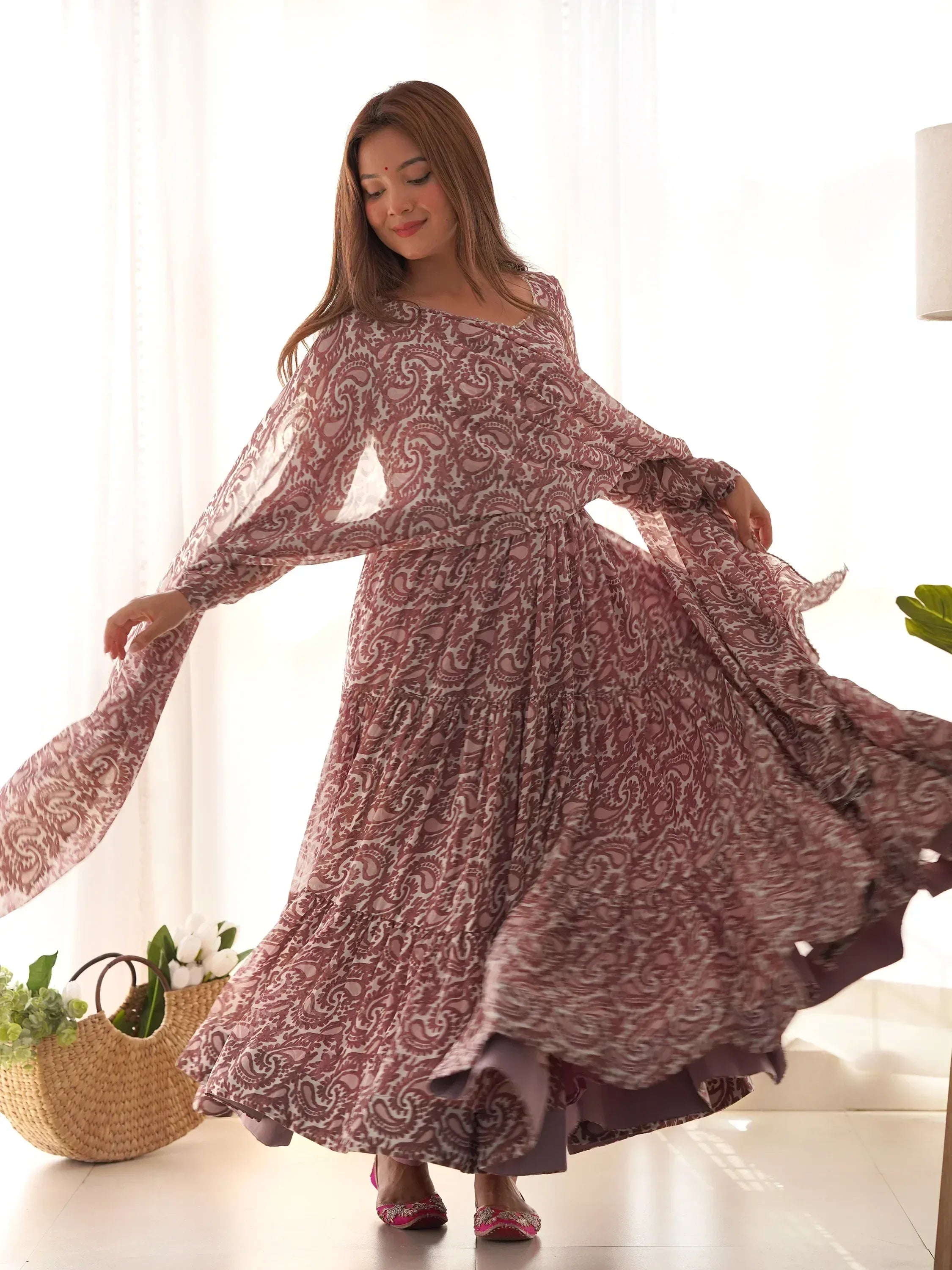 Woman twirling in a mauve printed ethnic gown with long sleeves indoors