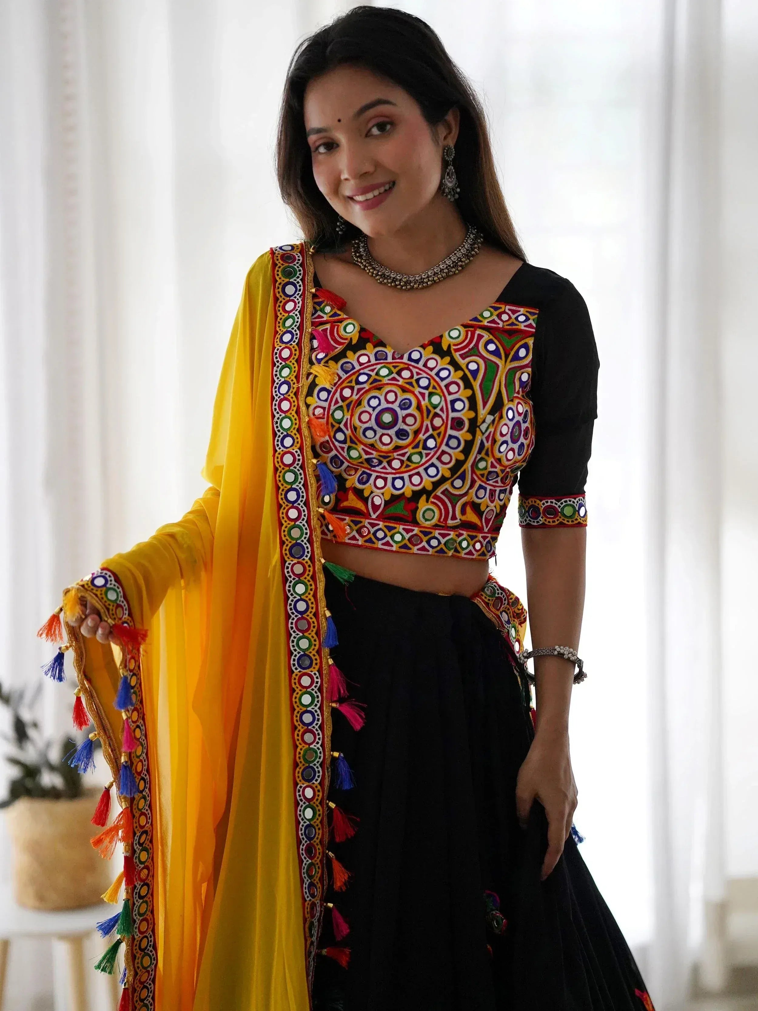 Black embroidered crop top with mirror work, yellow dupatta, and black skirt for Indian ethnic wear