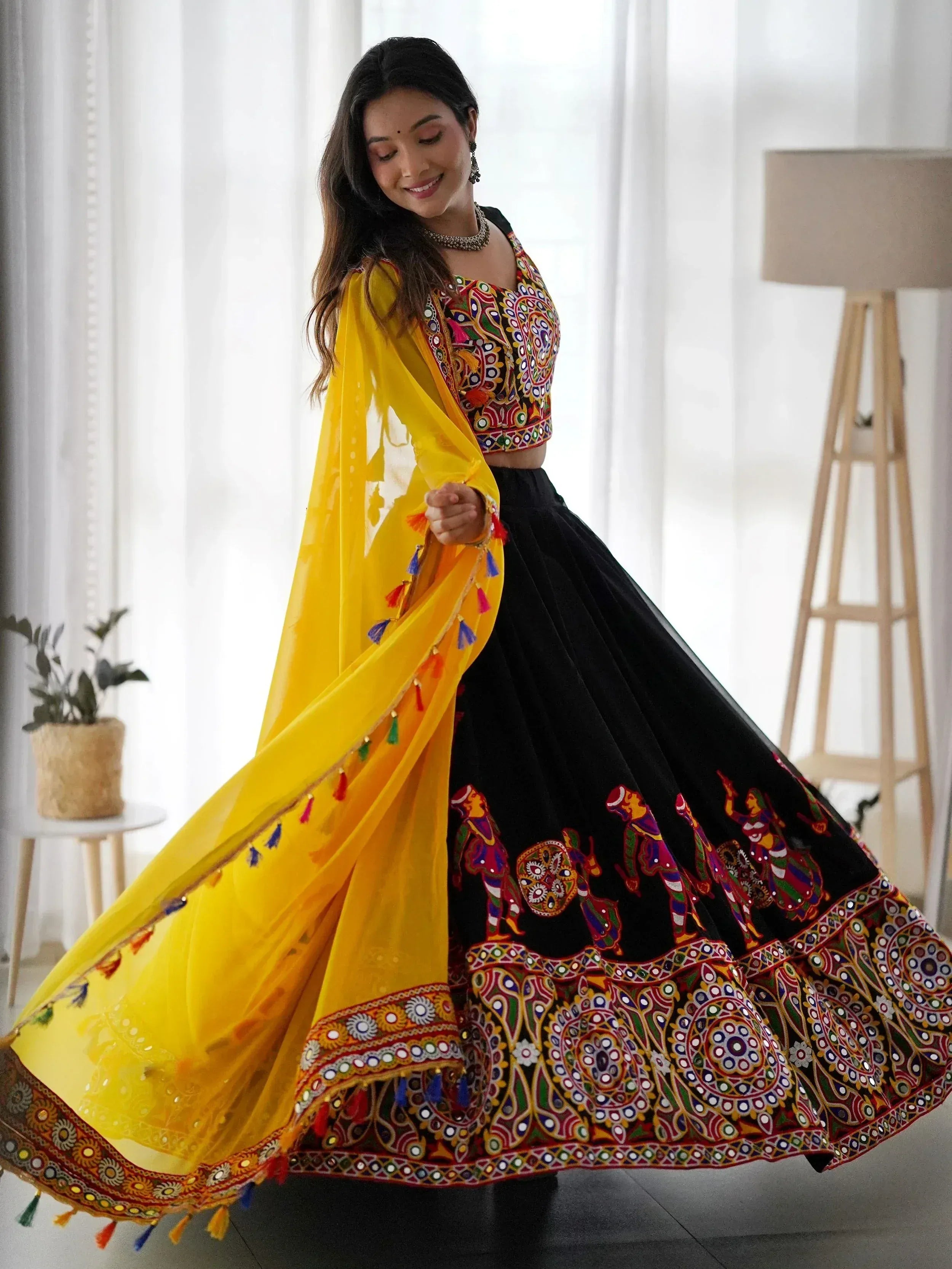 Black and yellow embroidered lehenga choli with mirror work and tassels, perfect for Indian ethnic wear.