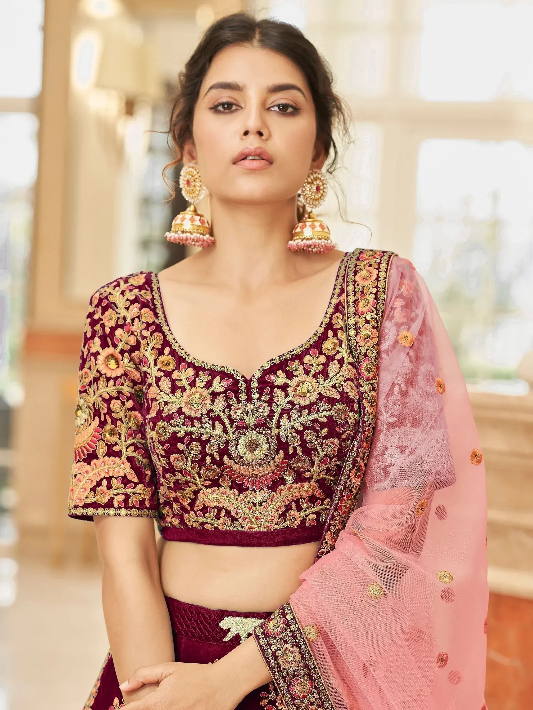 Maroon velvet lehenga choli with floral embroidery and pink net dupatta, perfect for Indian weddings and festive occasions.