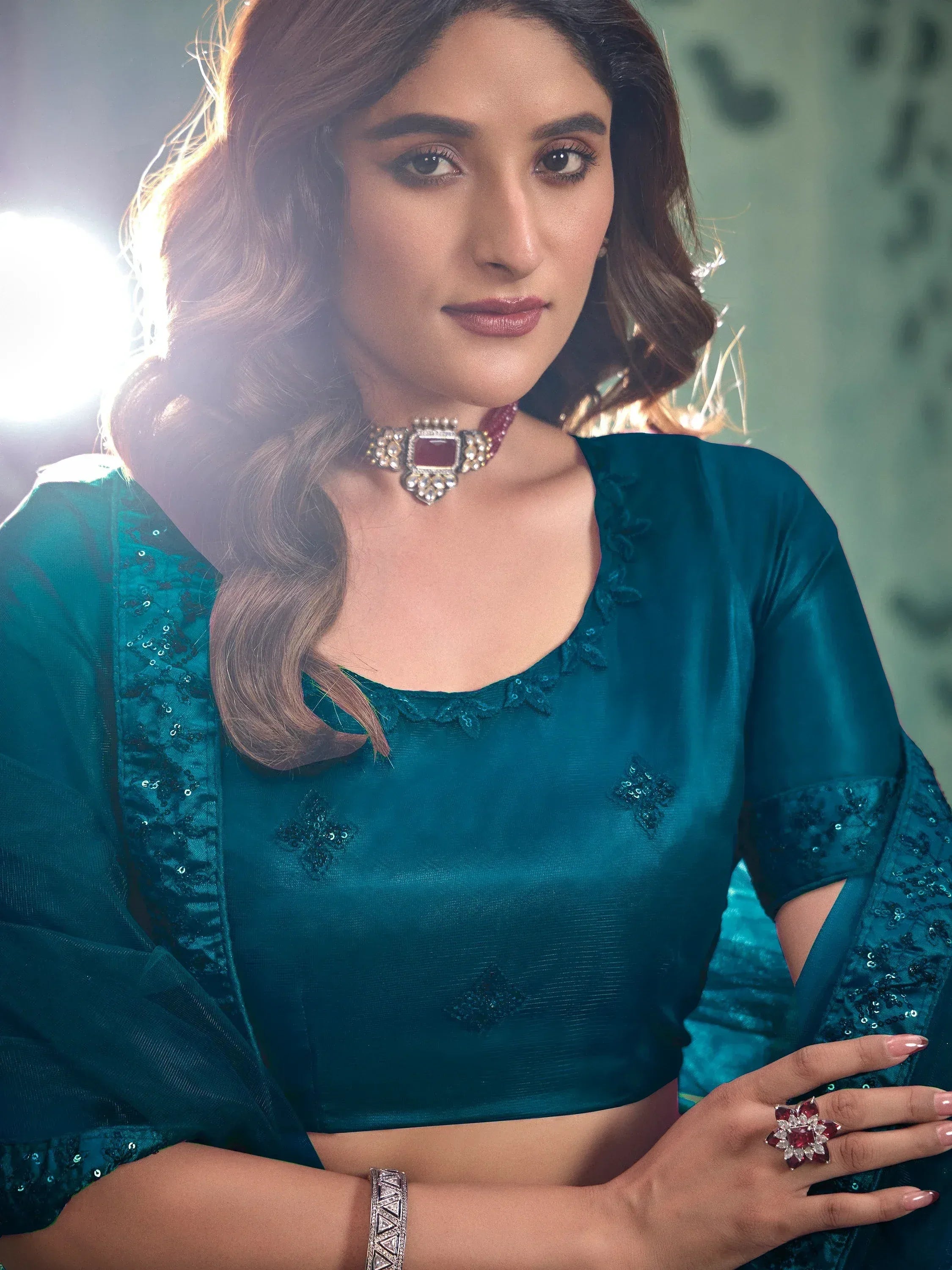 Teal designer lehenga choli with sequin embroidery, paired with statement jewelry for ethnic wear.