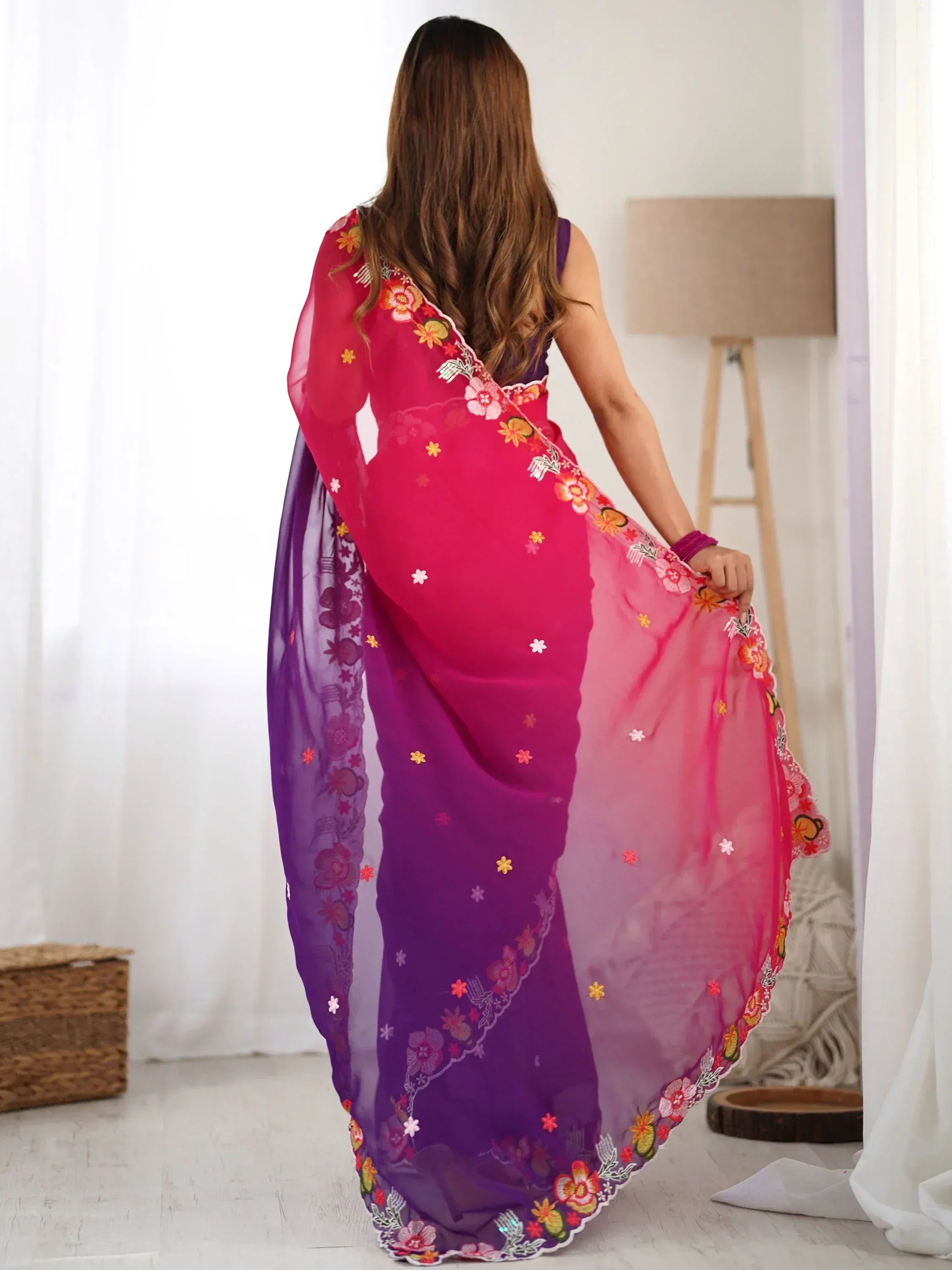 Woman in vibrant pink and purple embroidered saree with floral details, showcasing Indian ethnic wear