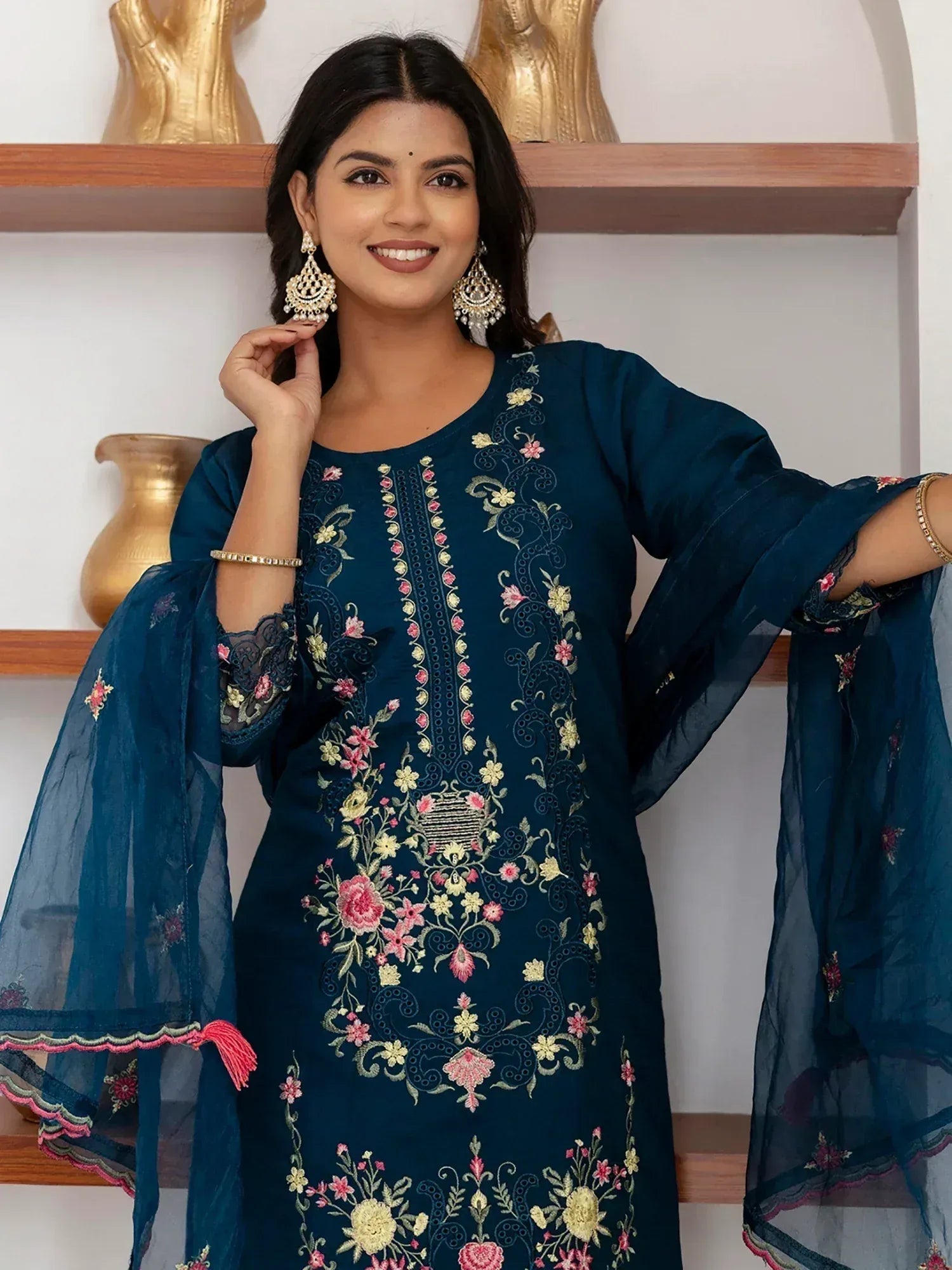 Woman in navy blue embroidered ethnic kurta with floral design and sheer sleeves, styled with jhumka earrings.