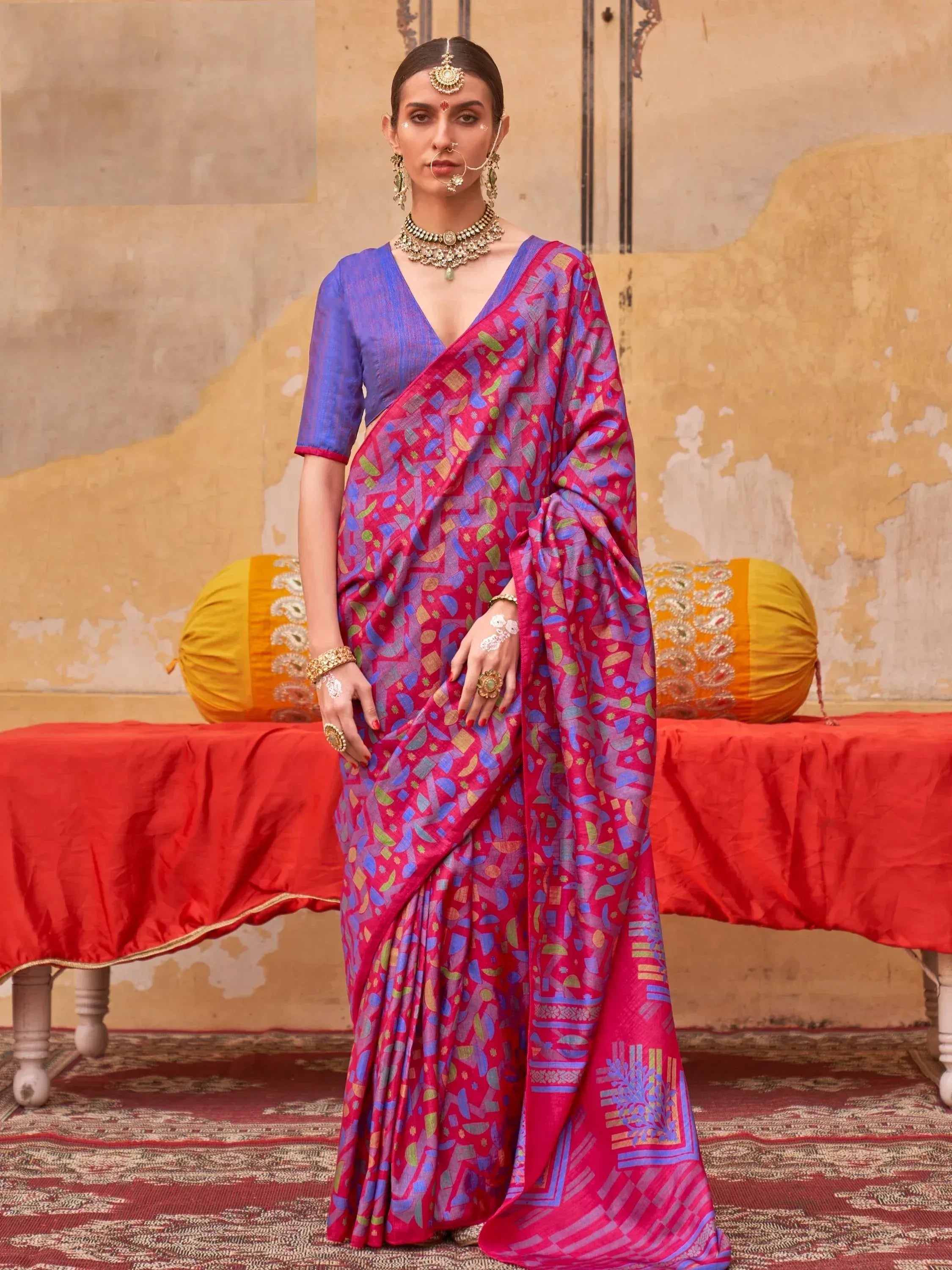 Woman in vibrant pink and blue printed saree with ethnic jewelry, perfect for Indian occasions
