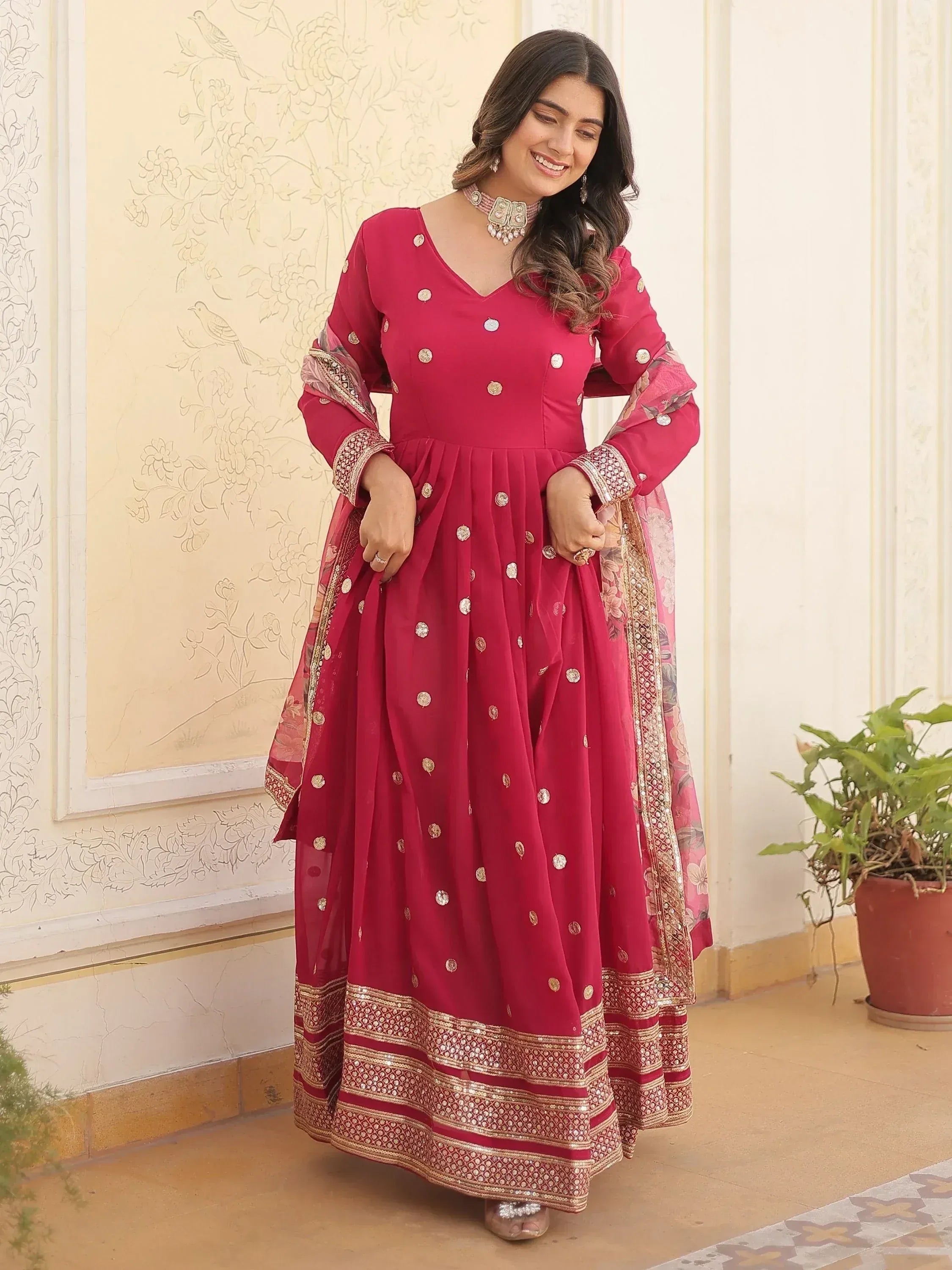 Woman in maroon ethnic anarkali gown with gold embroidery, perfect for Indian weddings or festive occasions.
