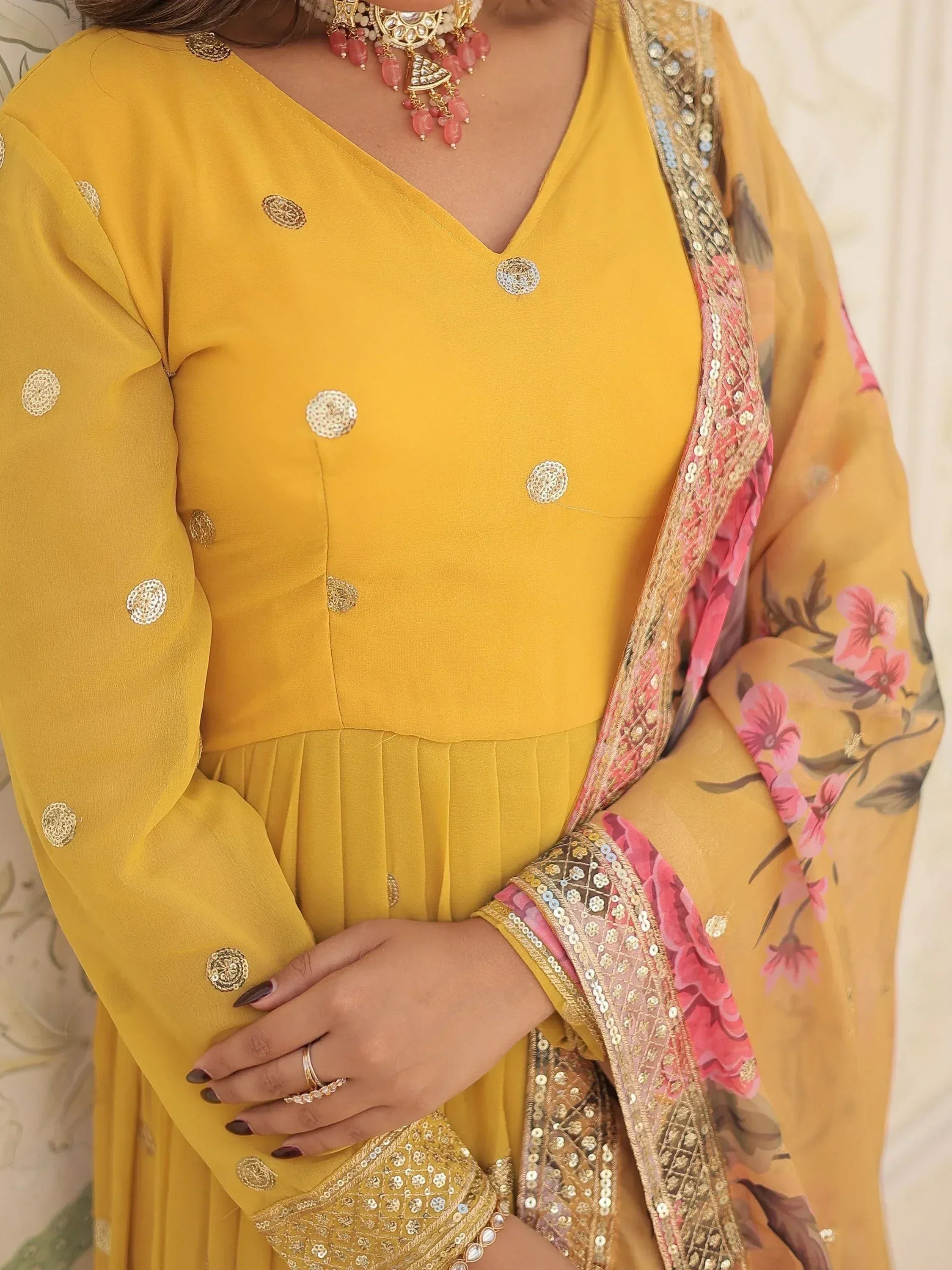 Yellow ethnic salwar kameez with floral dupatta, gold embroidery, and traditional jewelry