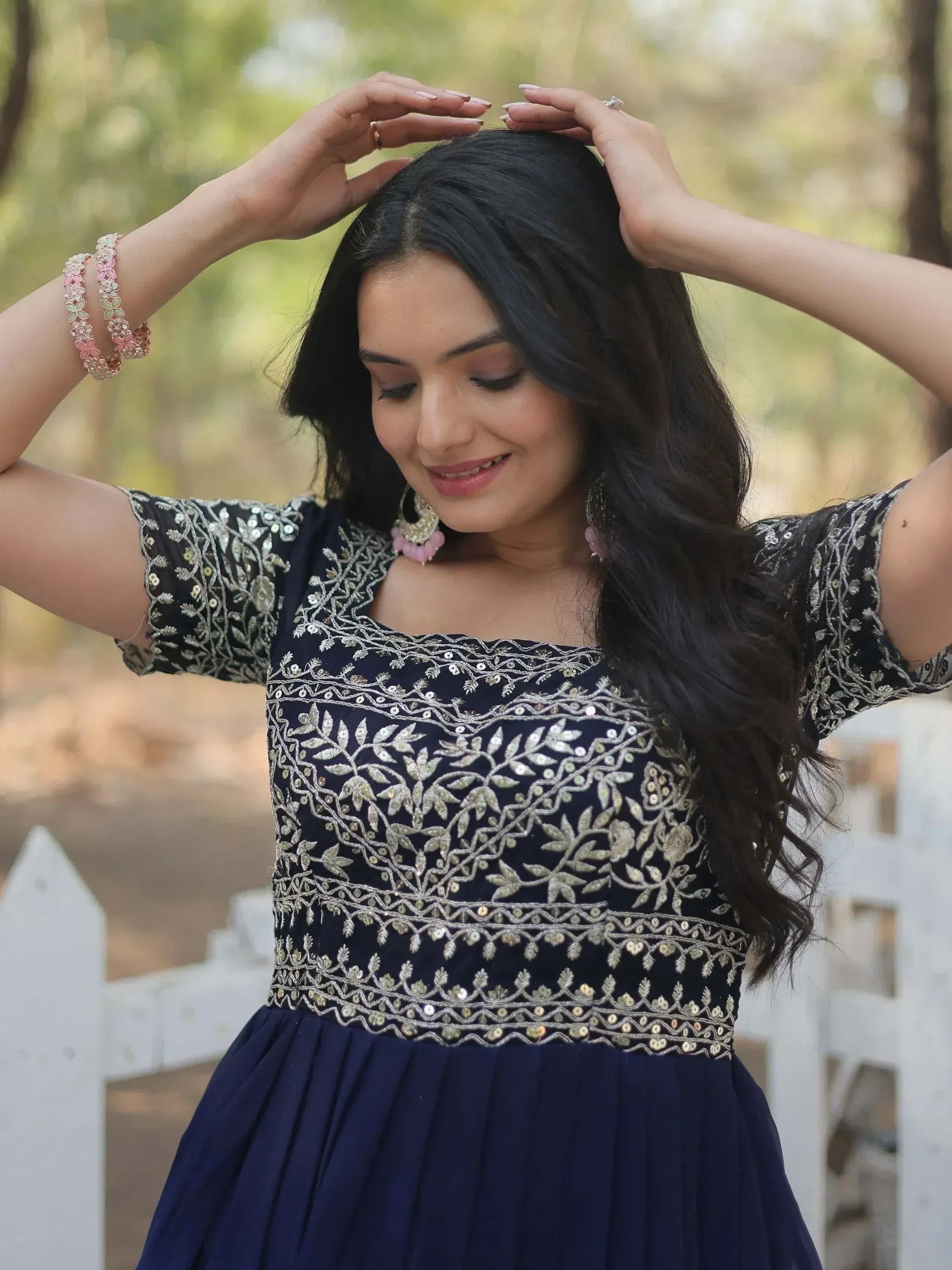 Woman in navy blue embroidered ethnic gown with floral sequin design, perfect for Indian occasions
