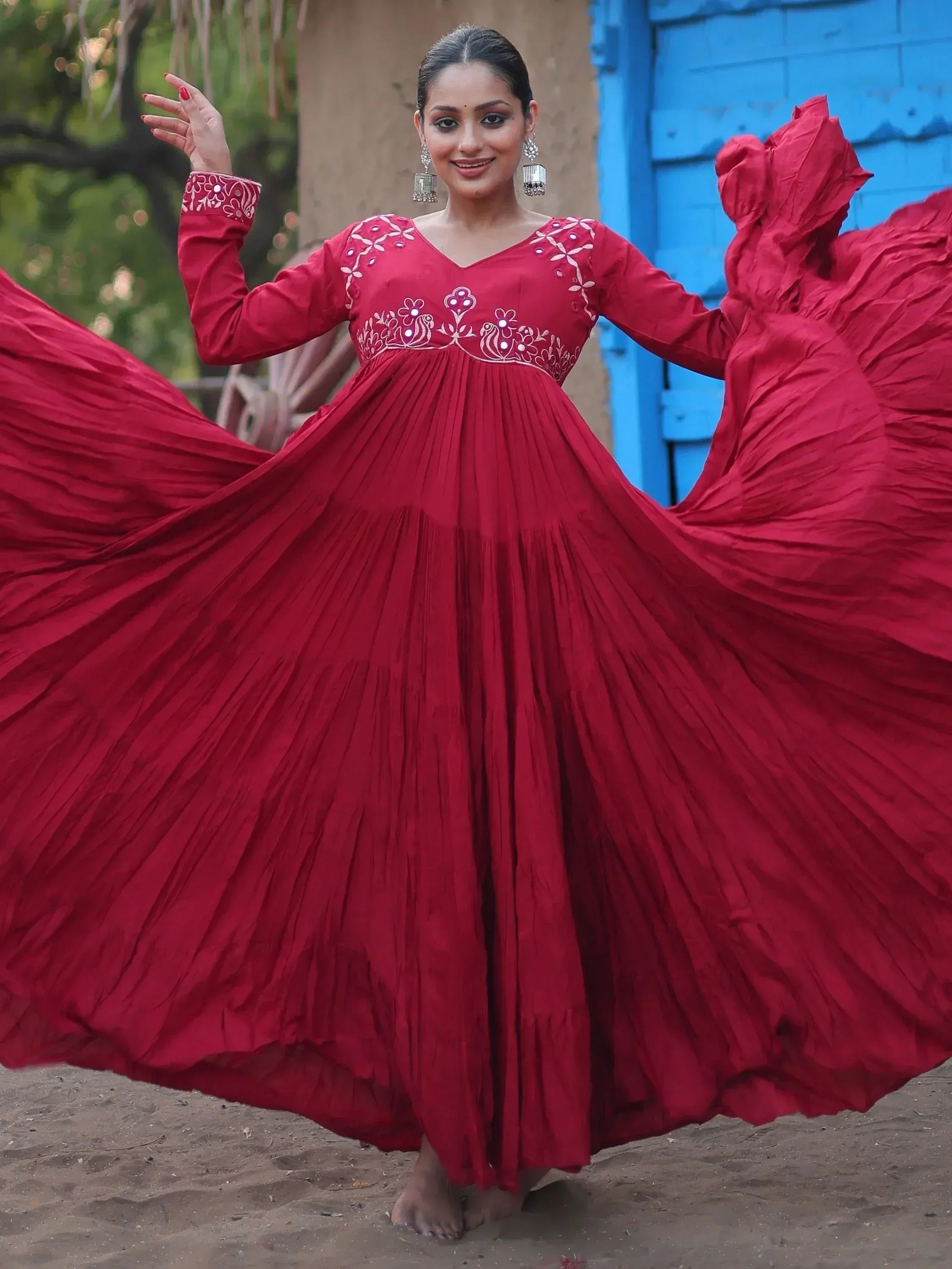 Red ethnic gown with floral embroidery, pleated skirt, and mirror work, perfect for festive occasions.