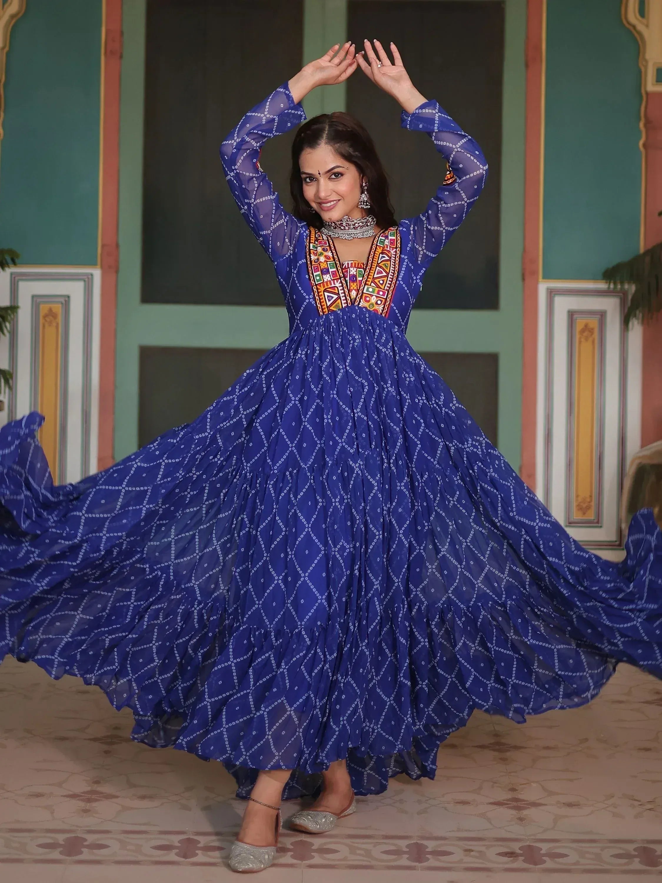Woman in blue ethnic gown with colorful embroidery, twirling in traditional Indian attire