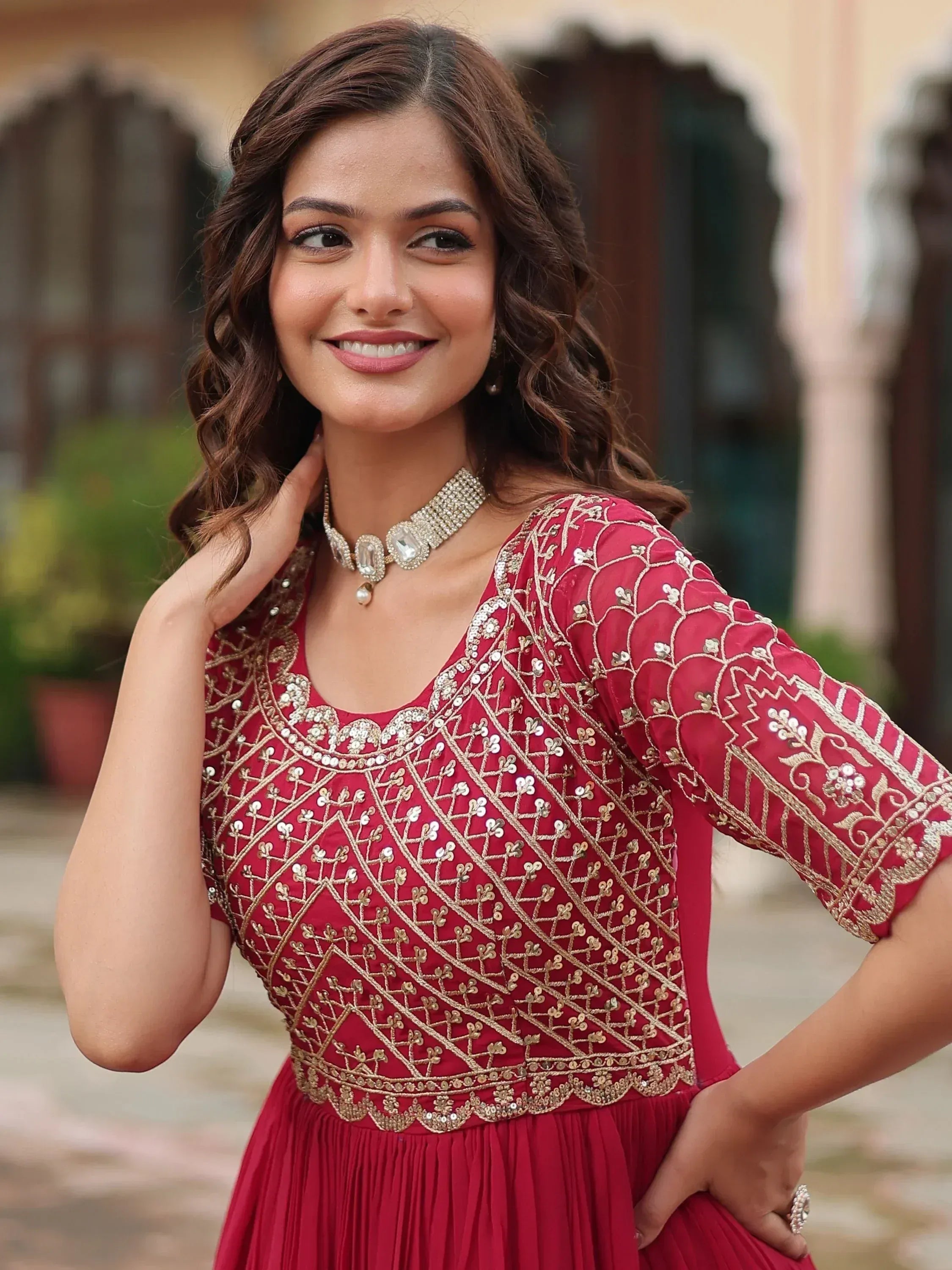 Woman in red embroidered ethnic gown with gold detailing, perfect for Indian occasions and festive wear.