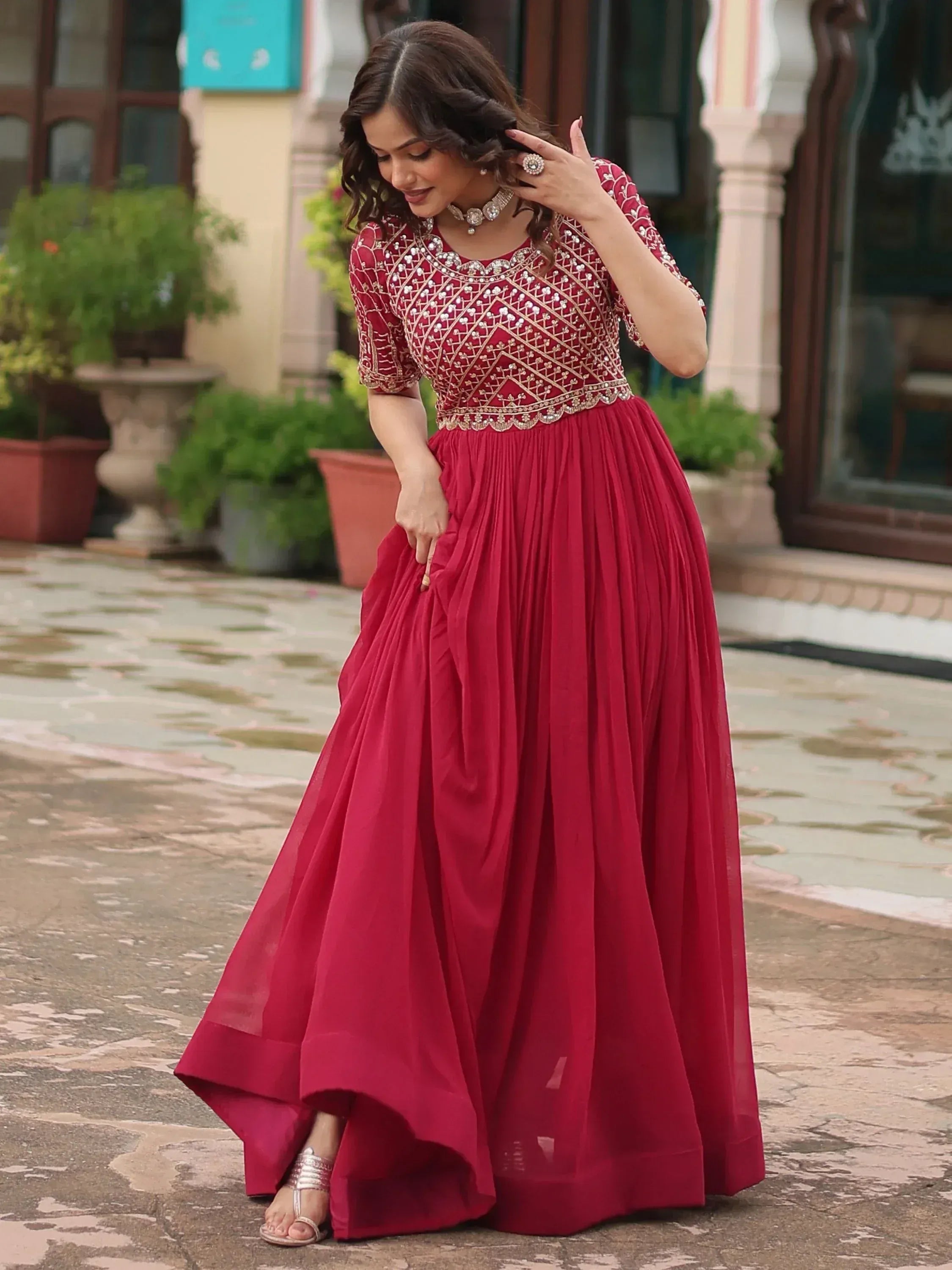 Woman in maroon ethnic gown with gold embroidery, perfect for Indian weddings or festive occasions.